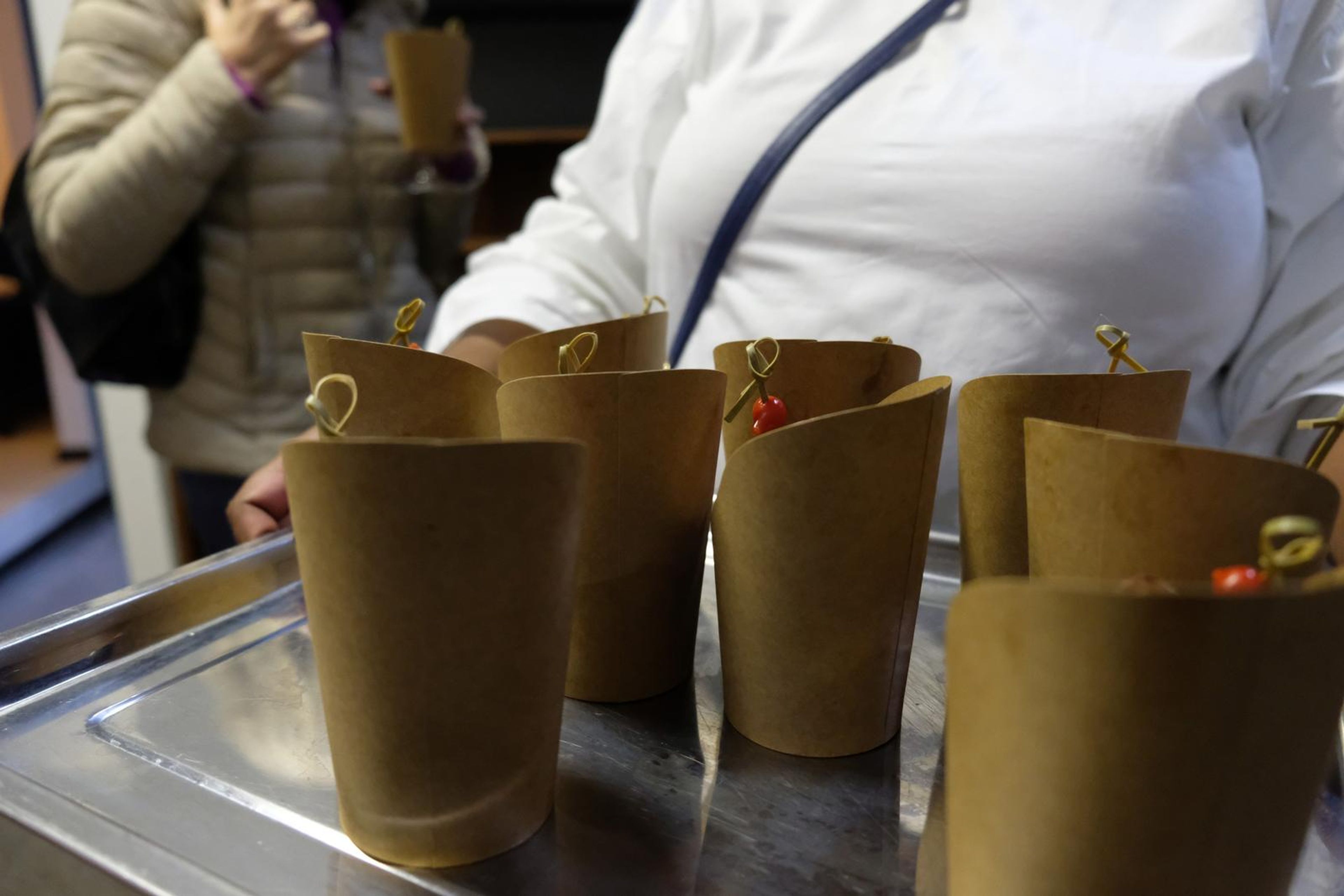 Waiter carrying a tray of paper cones filled with canapes
