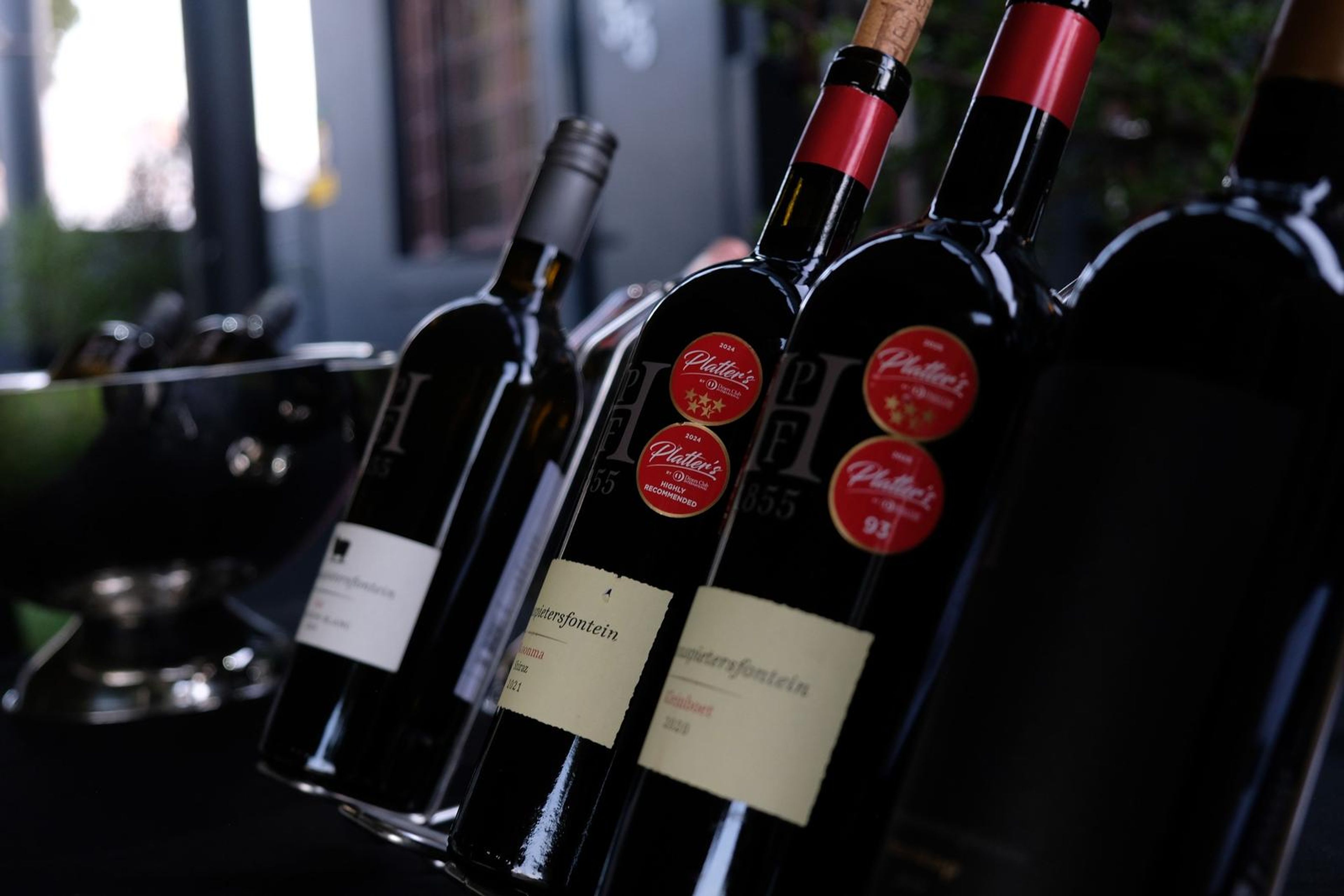 Wine bottles with red seals on a rack in front of the dark building