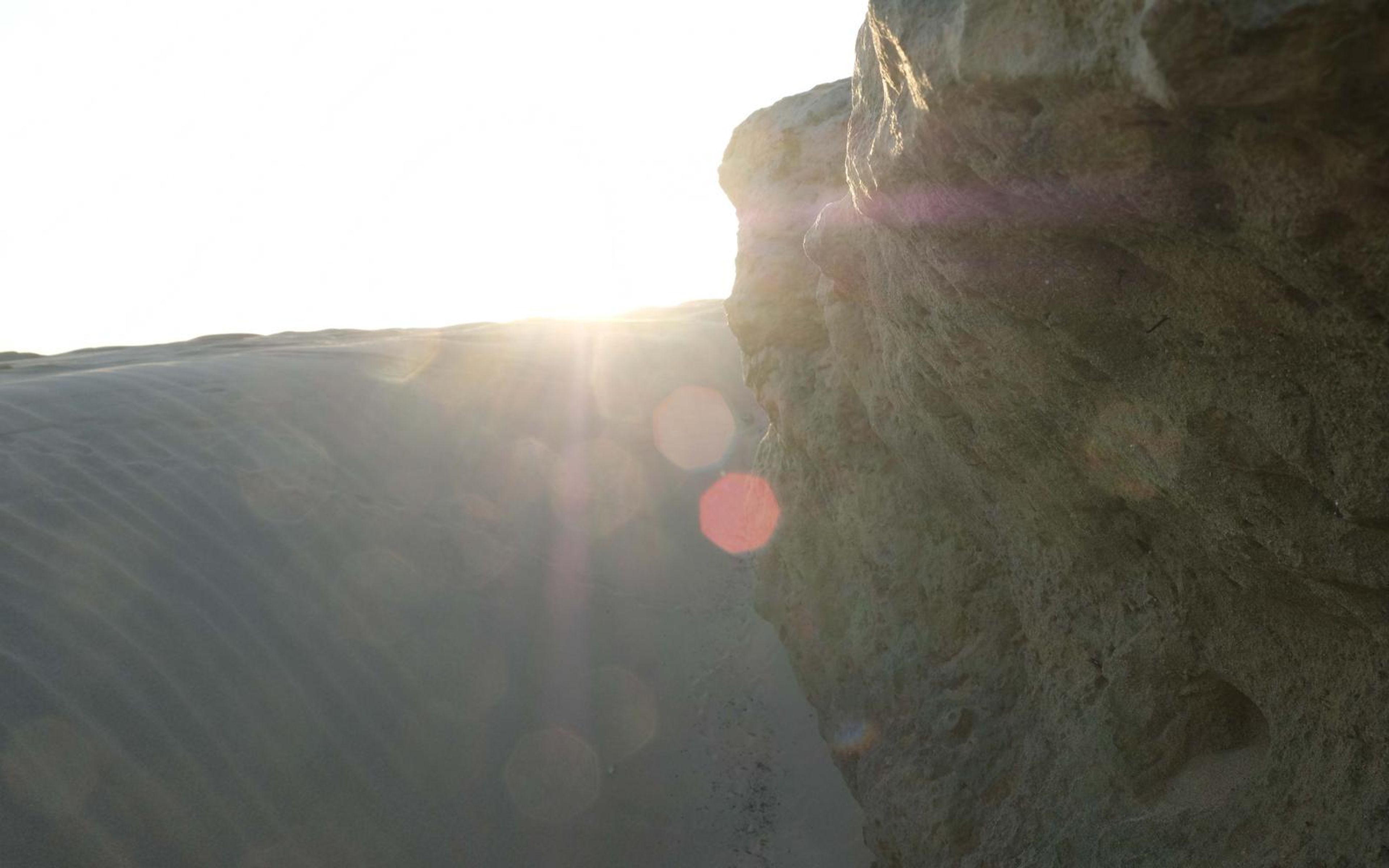 Sunburst between a limestone edge and a rippled dune, with lens flare