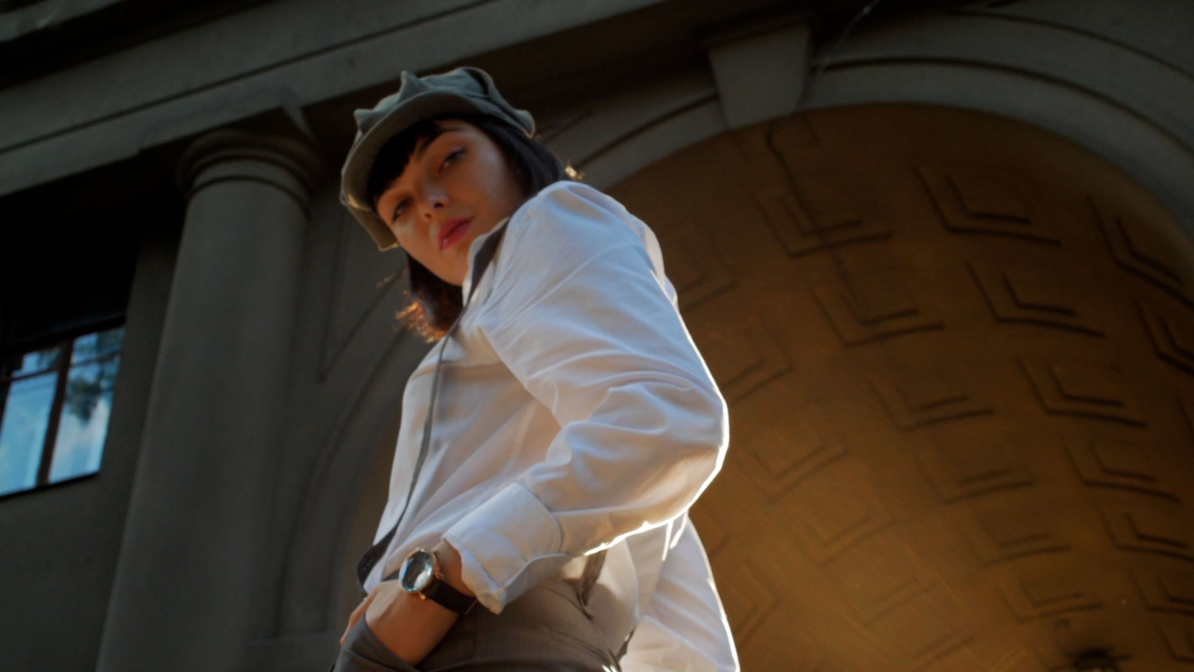 Woman in a white jacket standing in a stone archway
