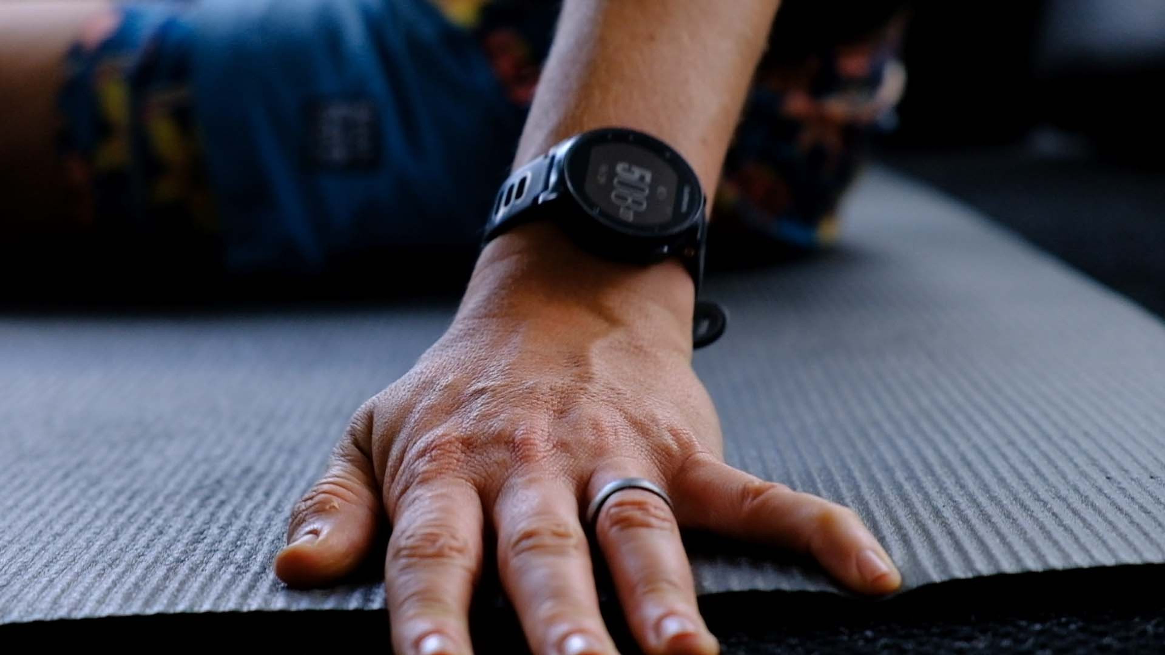 A hand resting on a grey exercise mat