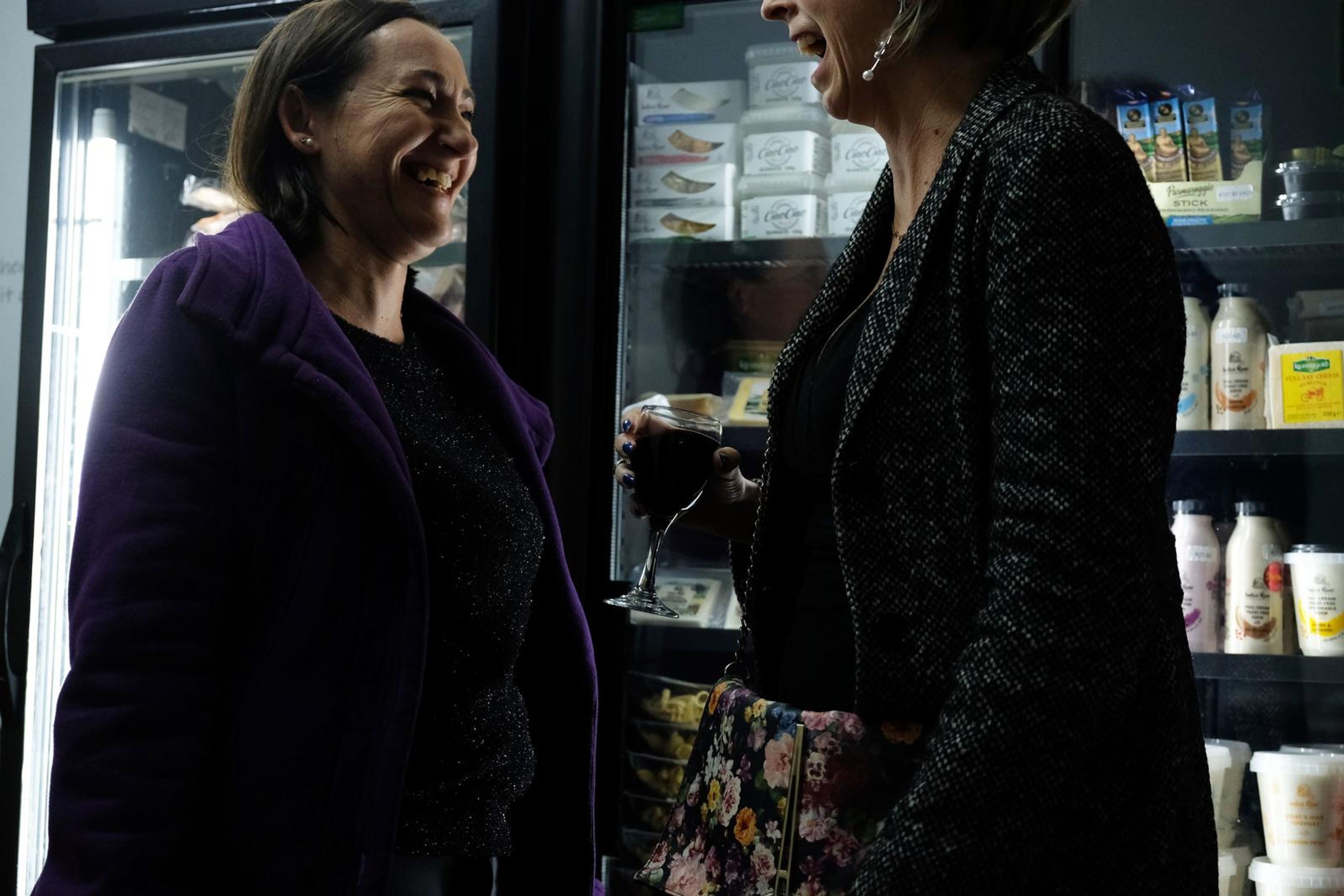 Smiling guest in a purple coat talking beside the fridge cabinets