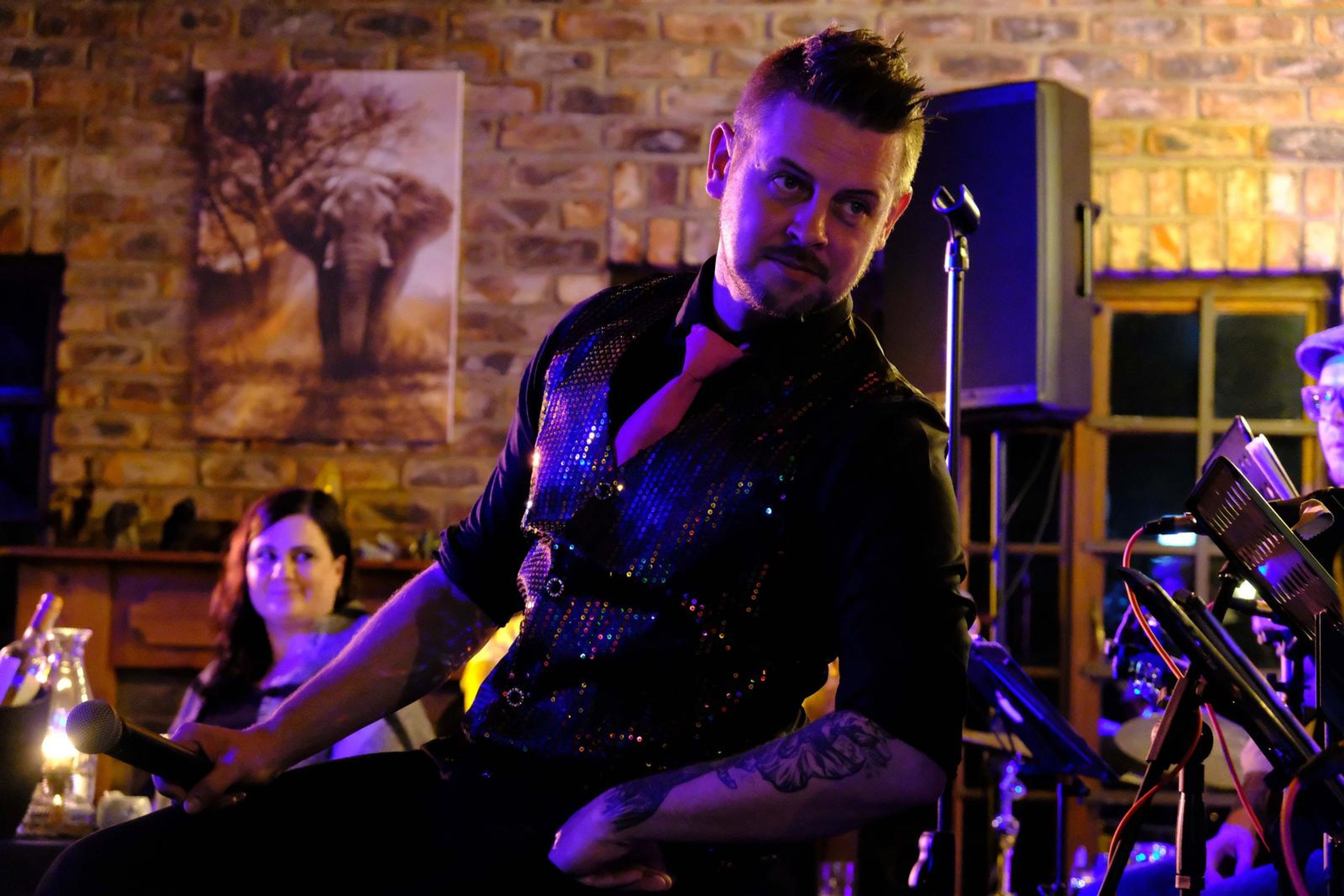 Lead singer glancing over his shoulder in front of an elephant photograph