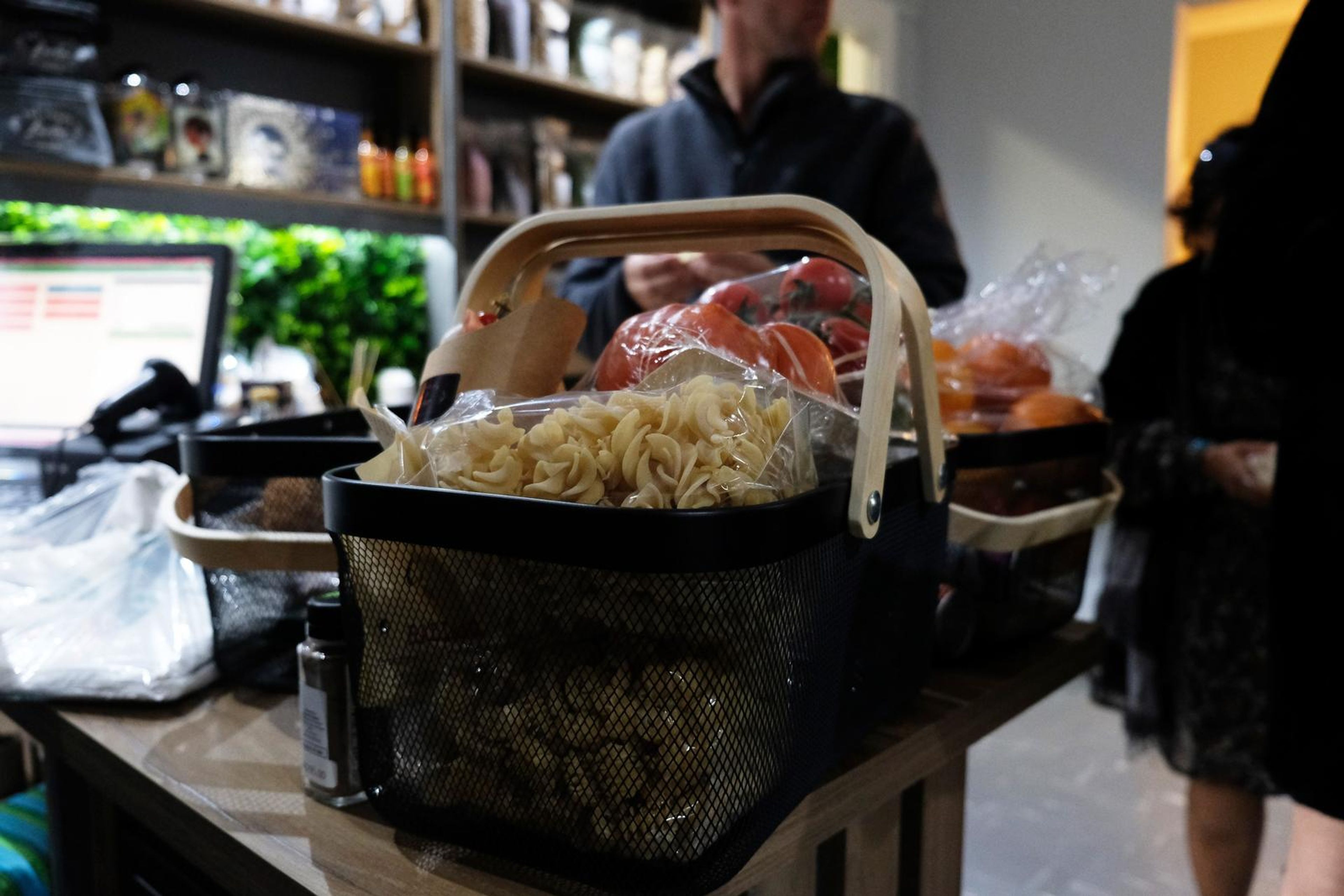 Basket of pasta and tomatoes on the counter with the till behind