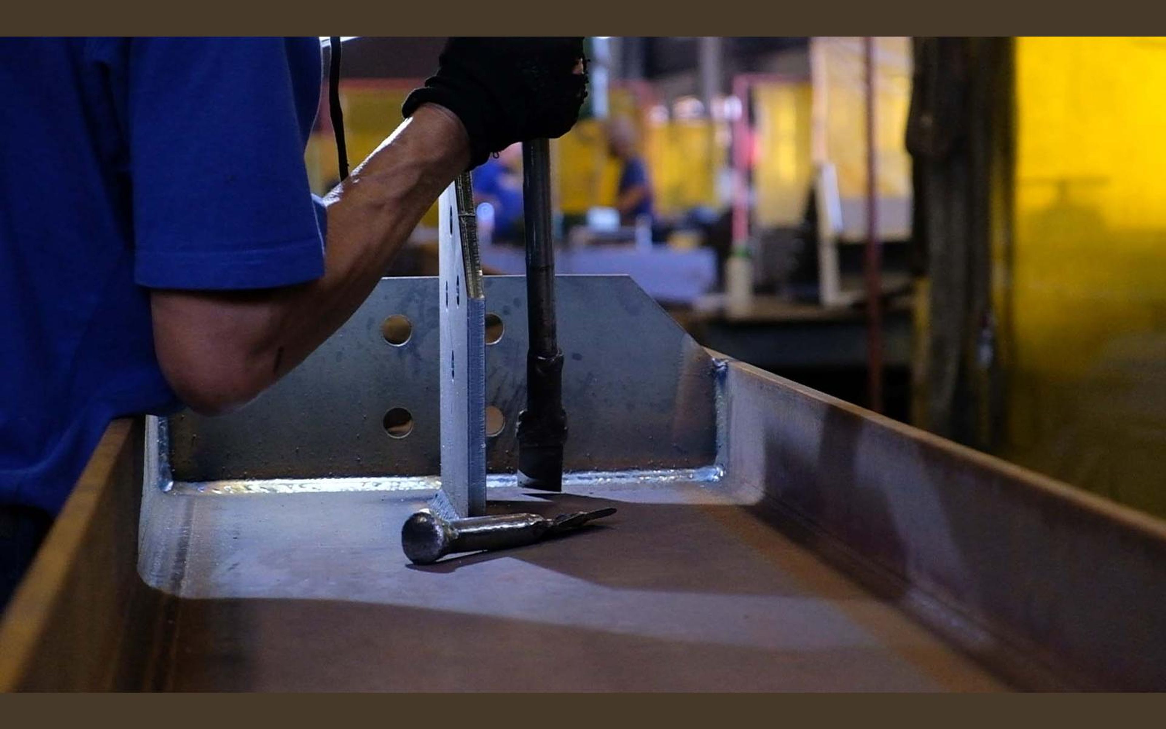 Fabricator in a ROVD shirt working at a steel bench