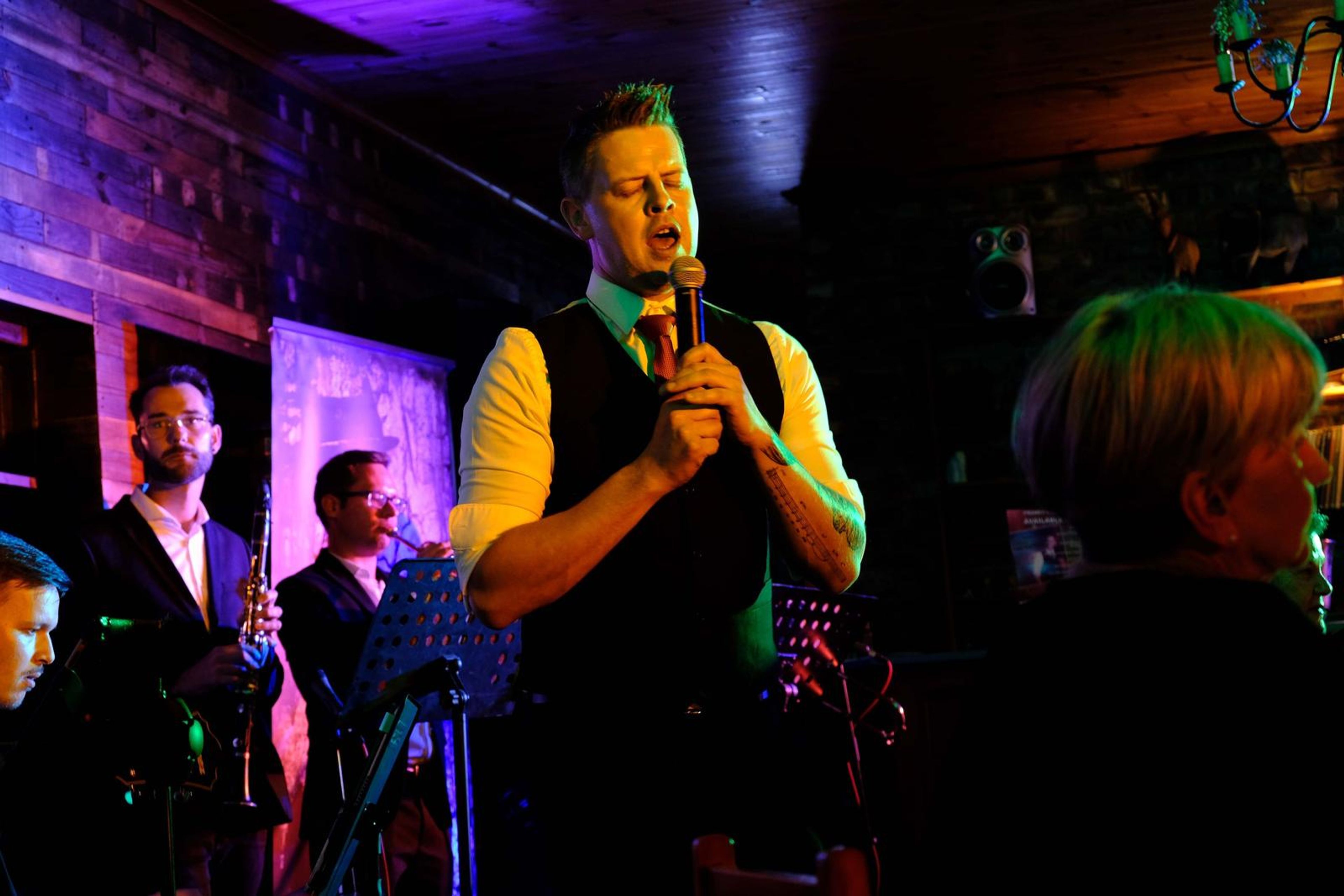 Singer in a waistcoat singing in front of the band