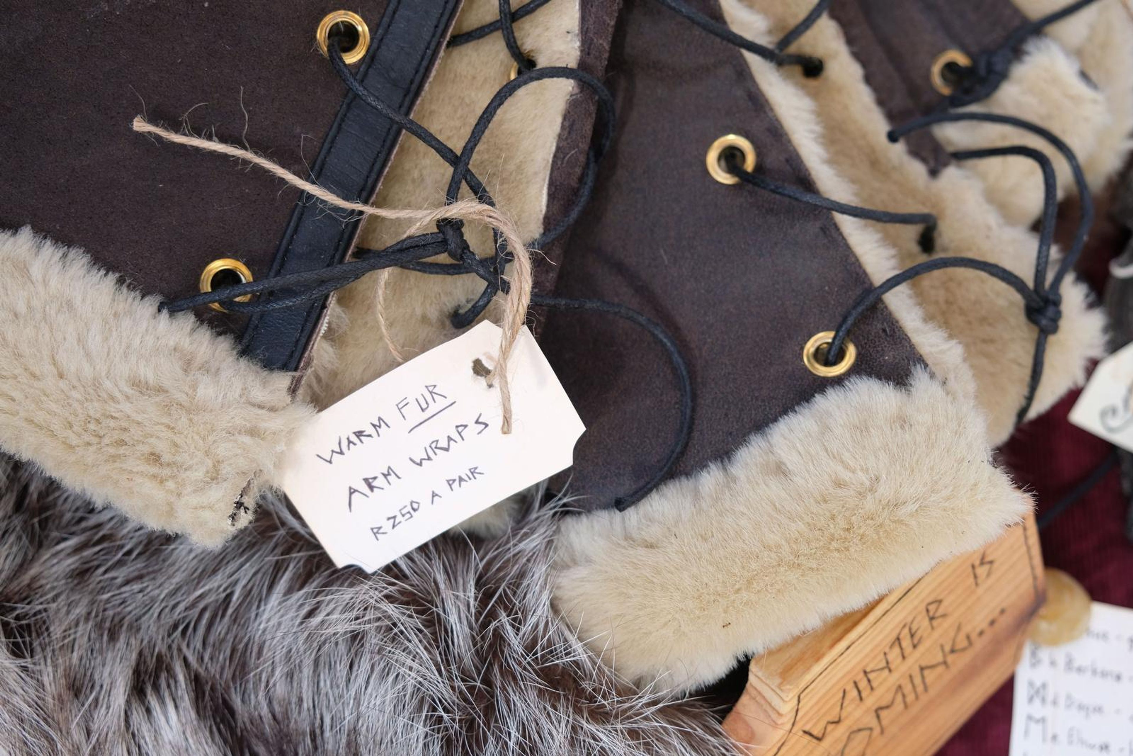 Close-up of fur-lined leather arm wraps with eyelets and black lacing