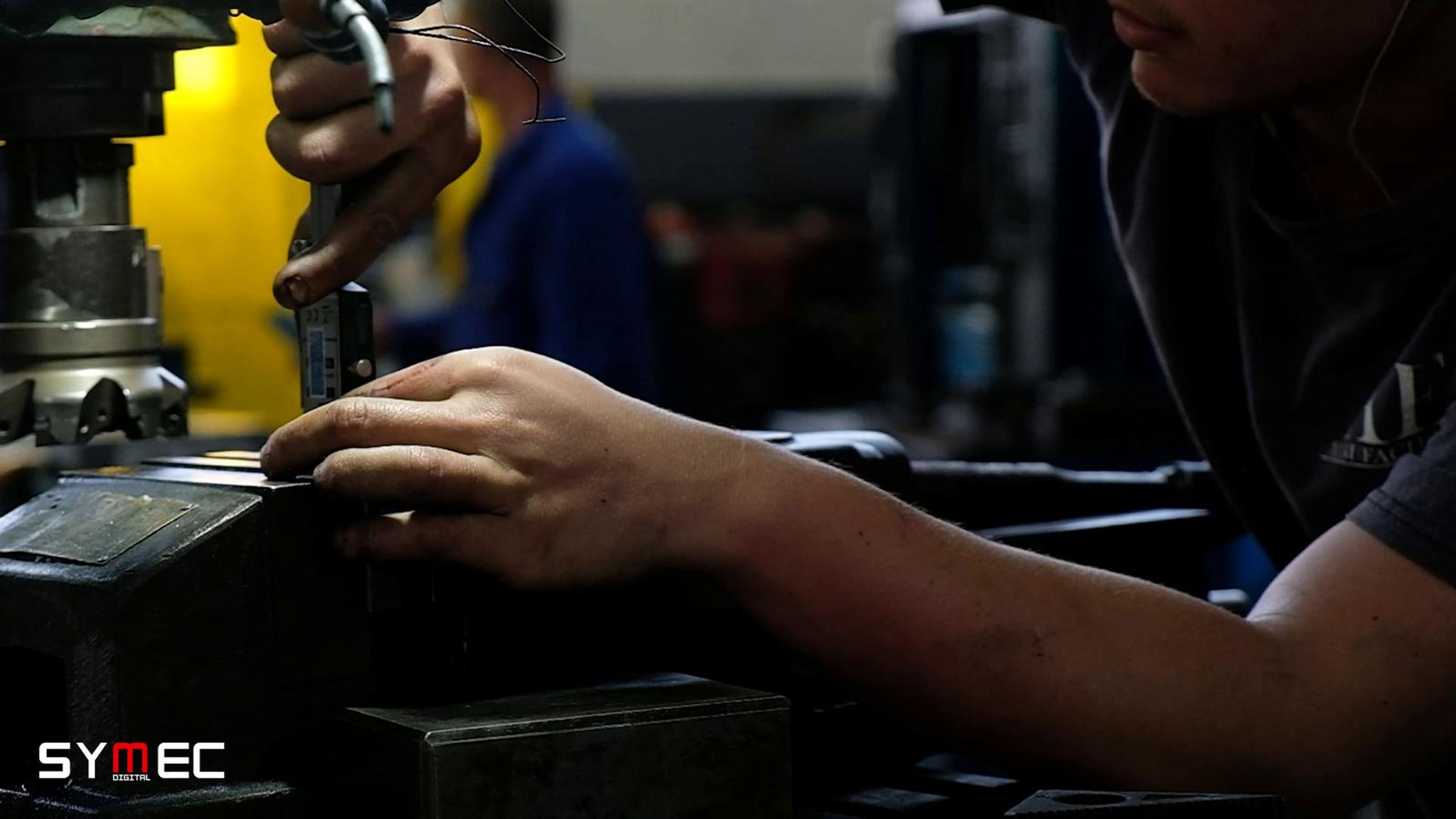 Hands working a part at a machine