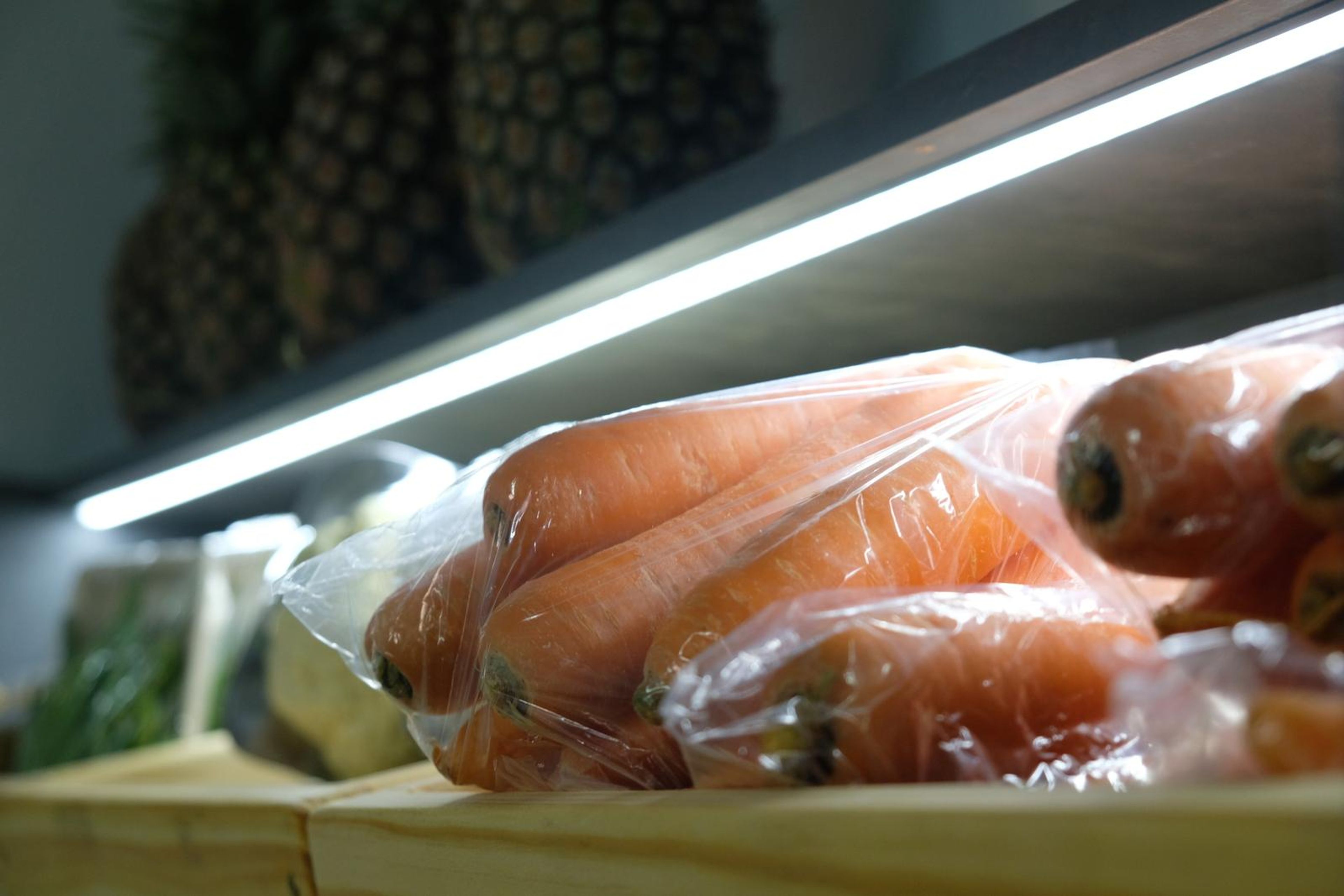 Packed carrots on the chilled produce shelf under strip lighting