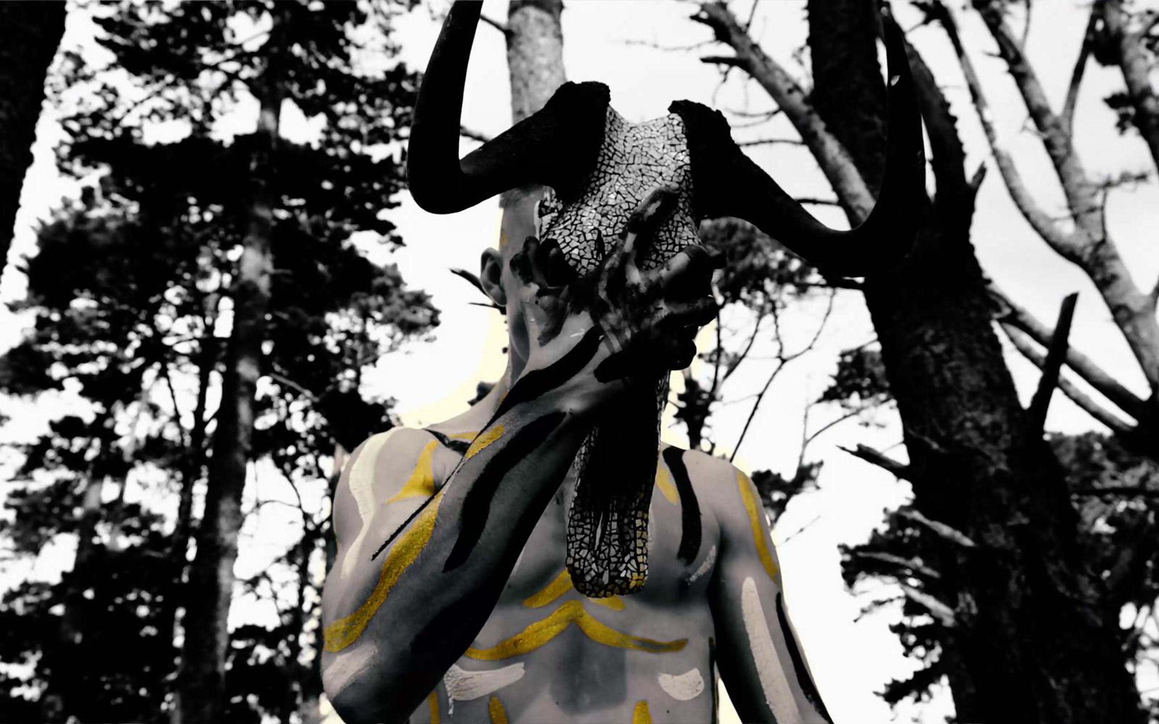 Performer from behind with a skull on his shoulder, painted back and arms in black and white