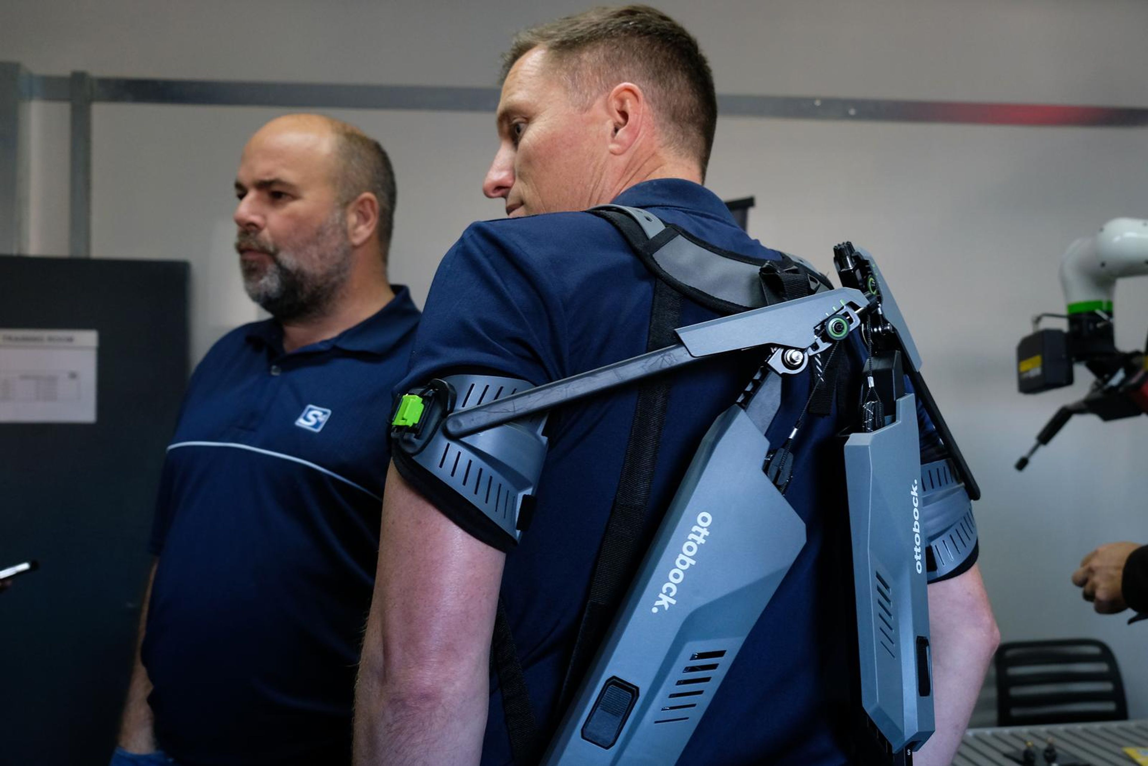 Two men at the SuitX stand, one wearing an exoskeleton