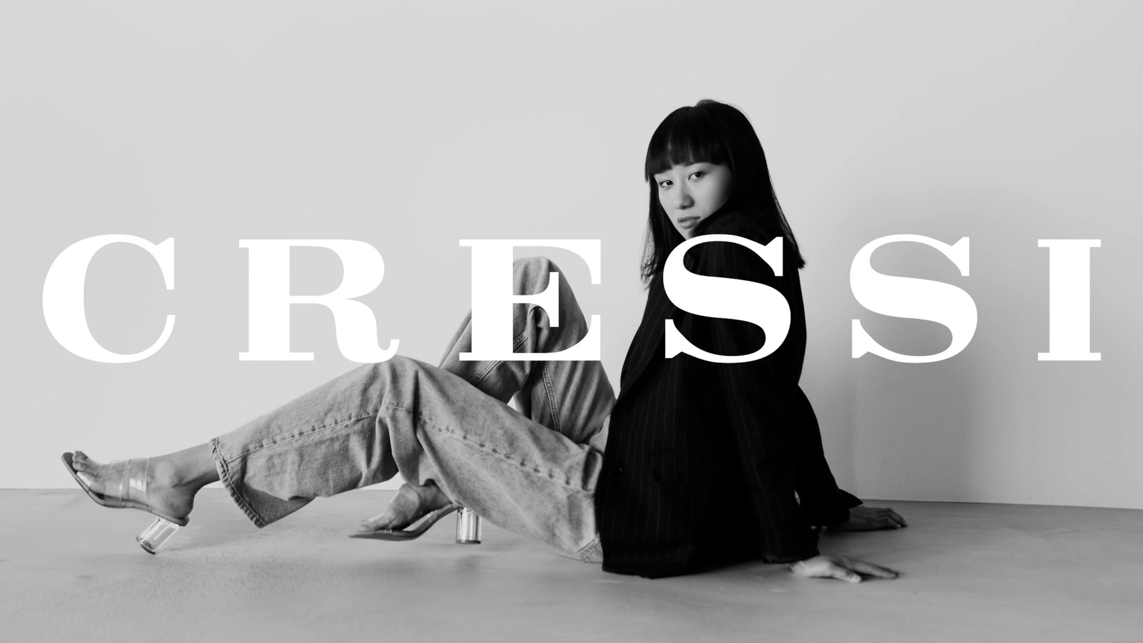 Woman in grey trousers seated on a white floor beneath the CRESSI wordmark