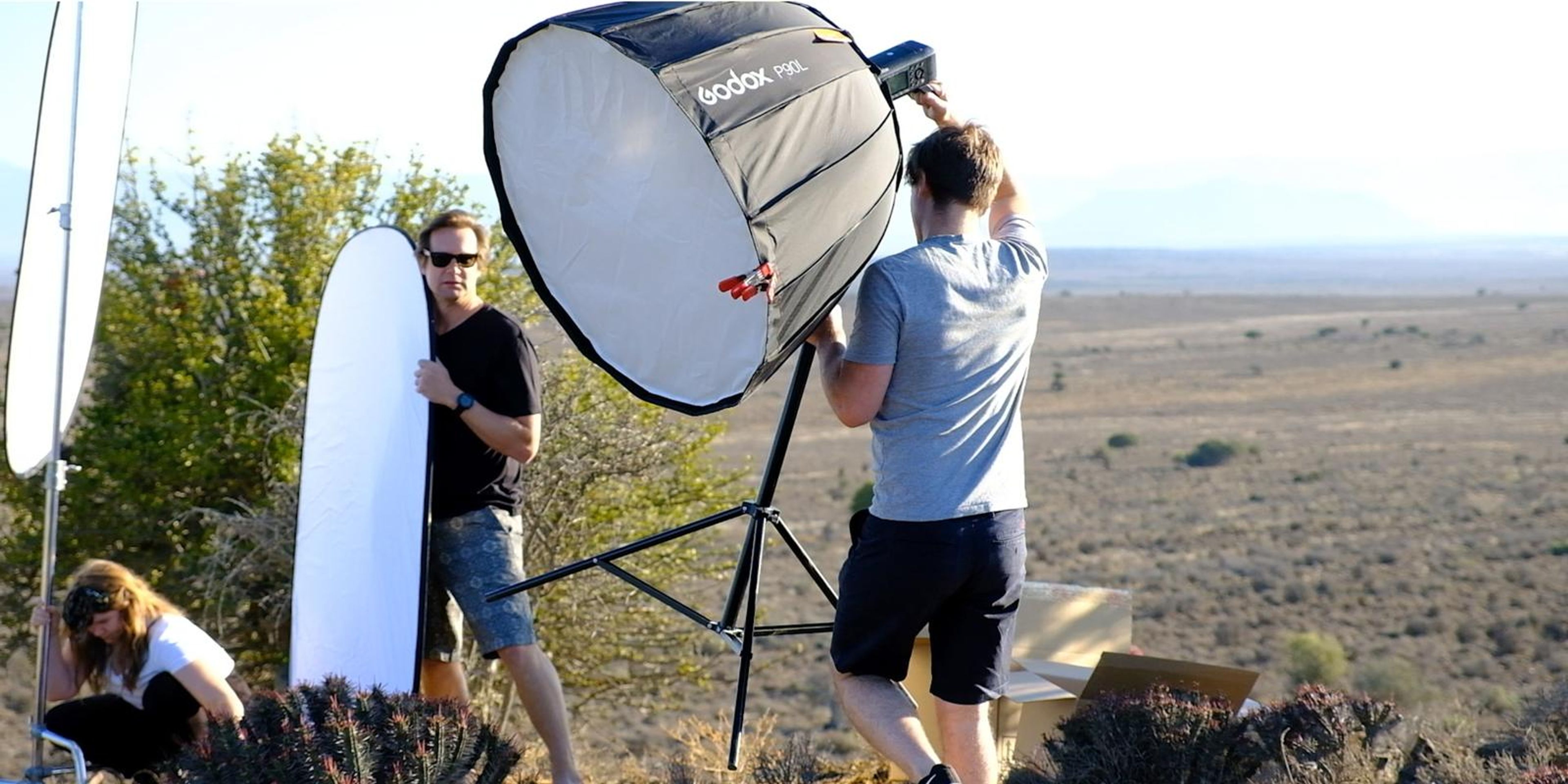 Crew setting up a softbox and reflector on the veld