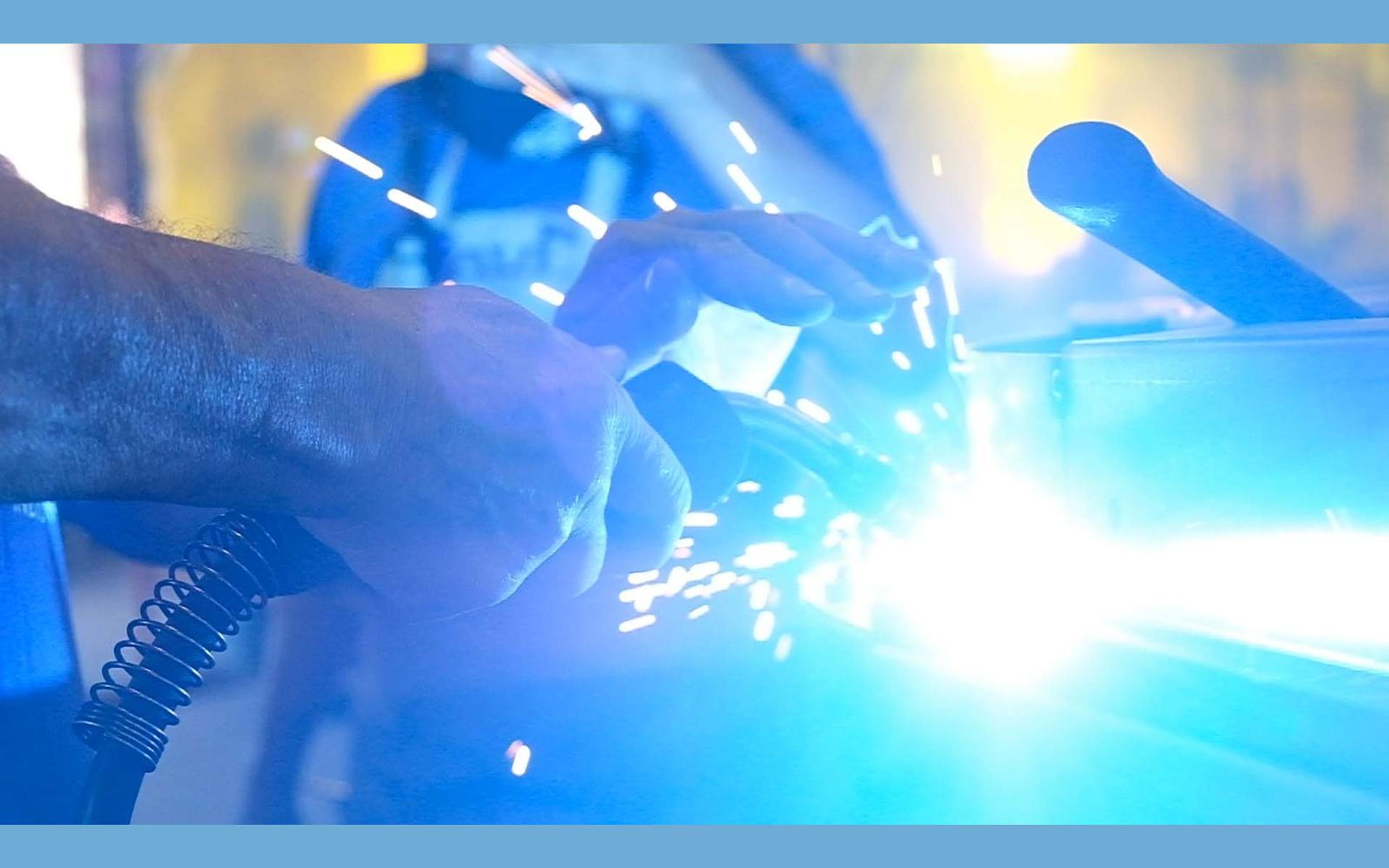 Welding glow lighting the steel and the welder's mask