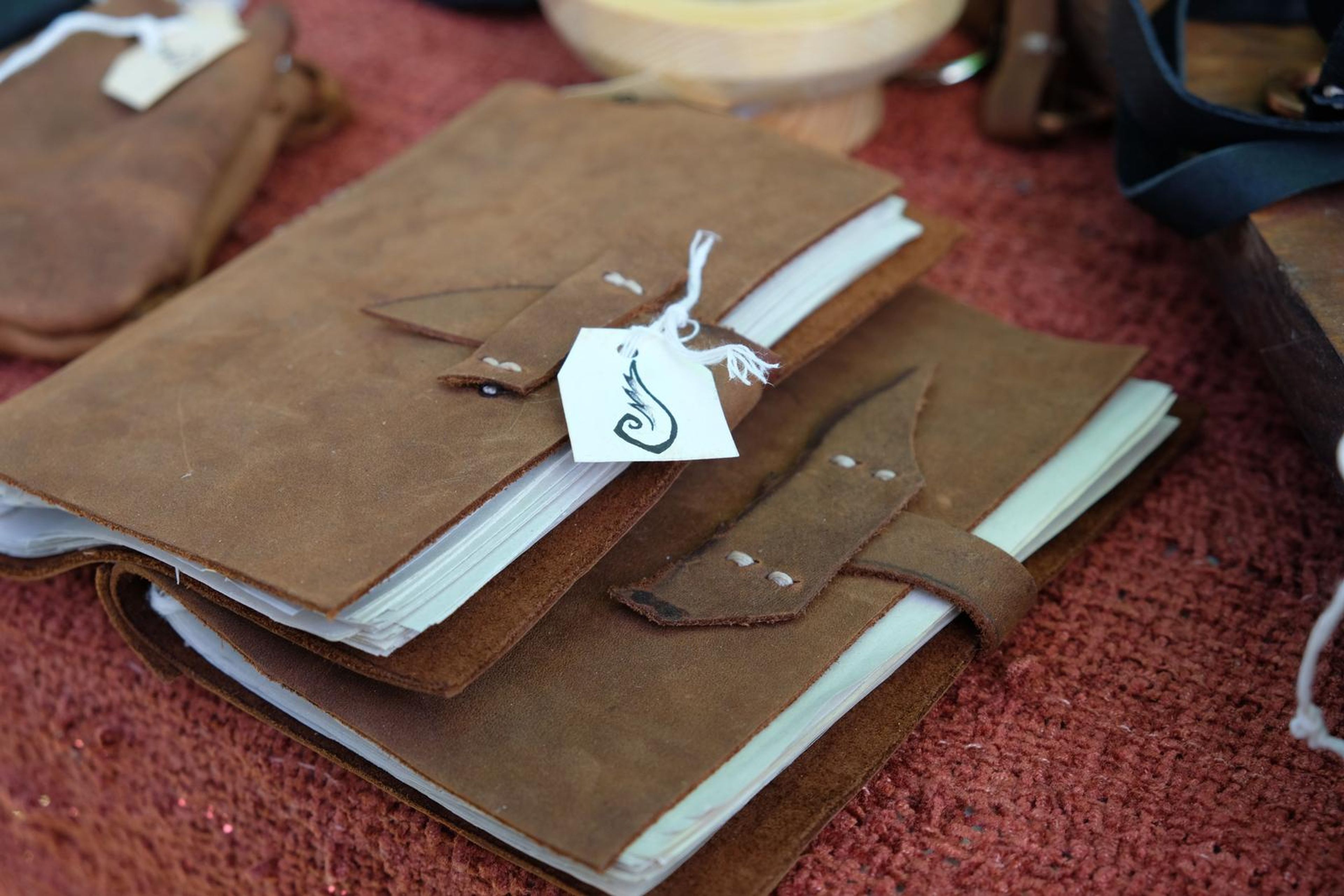 Handmade tan leather journal with a strap closure and tag