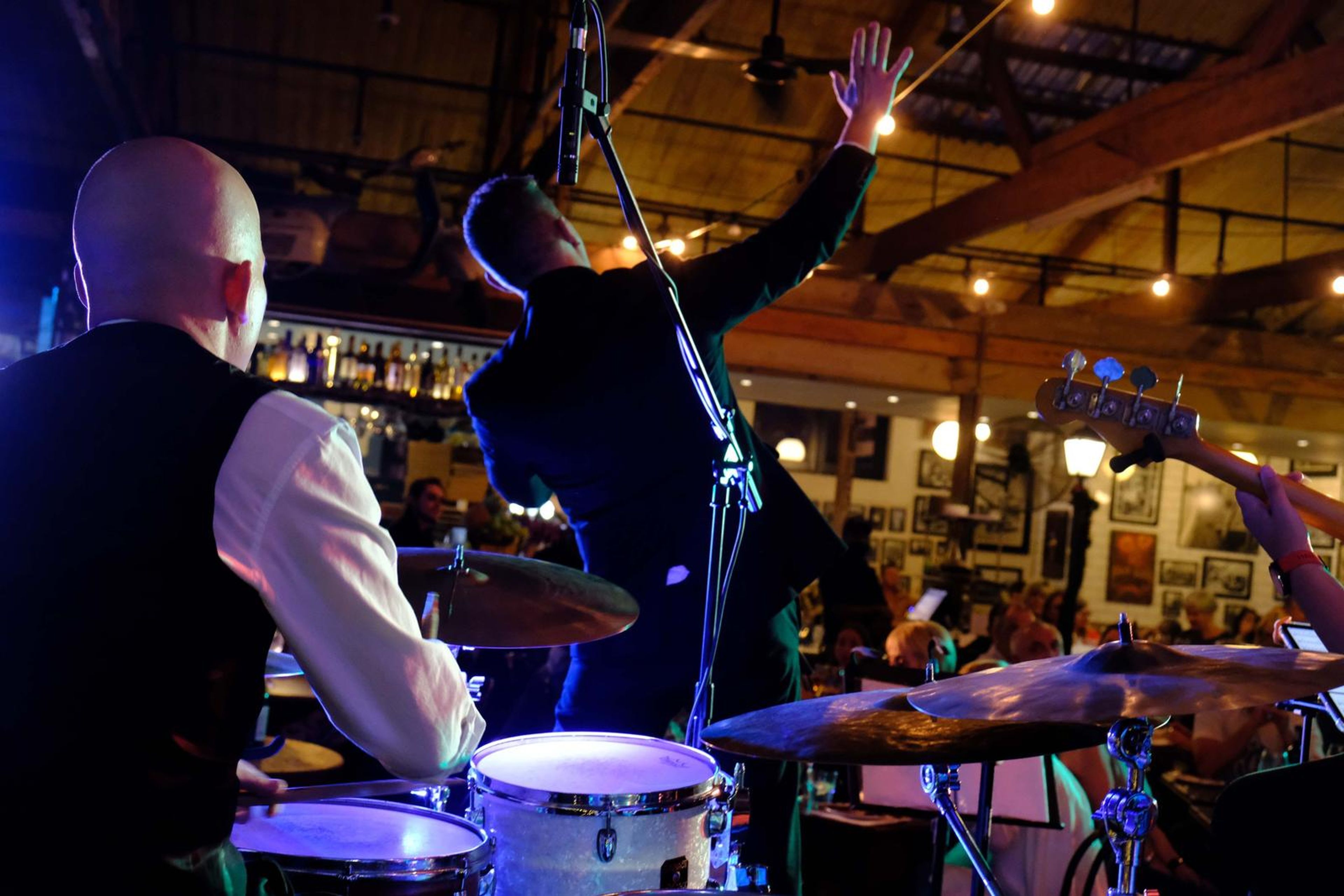 Drummer and a singer with his arm raised at the front of the stage