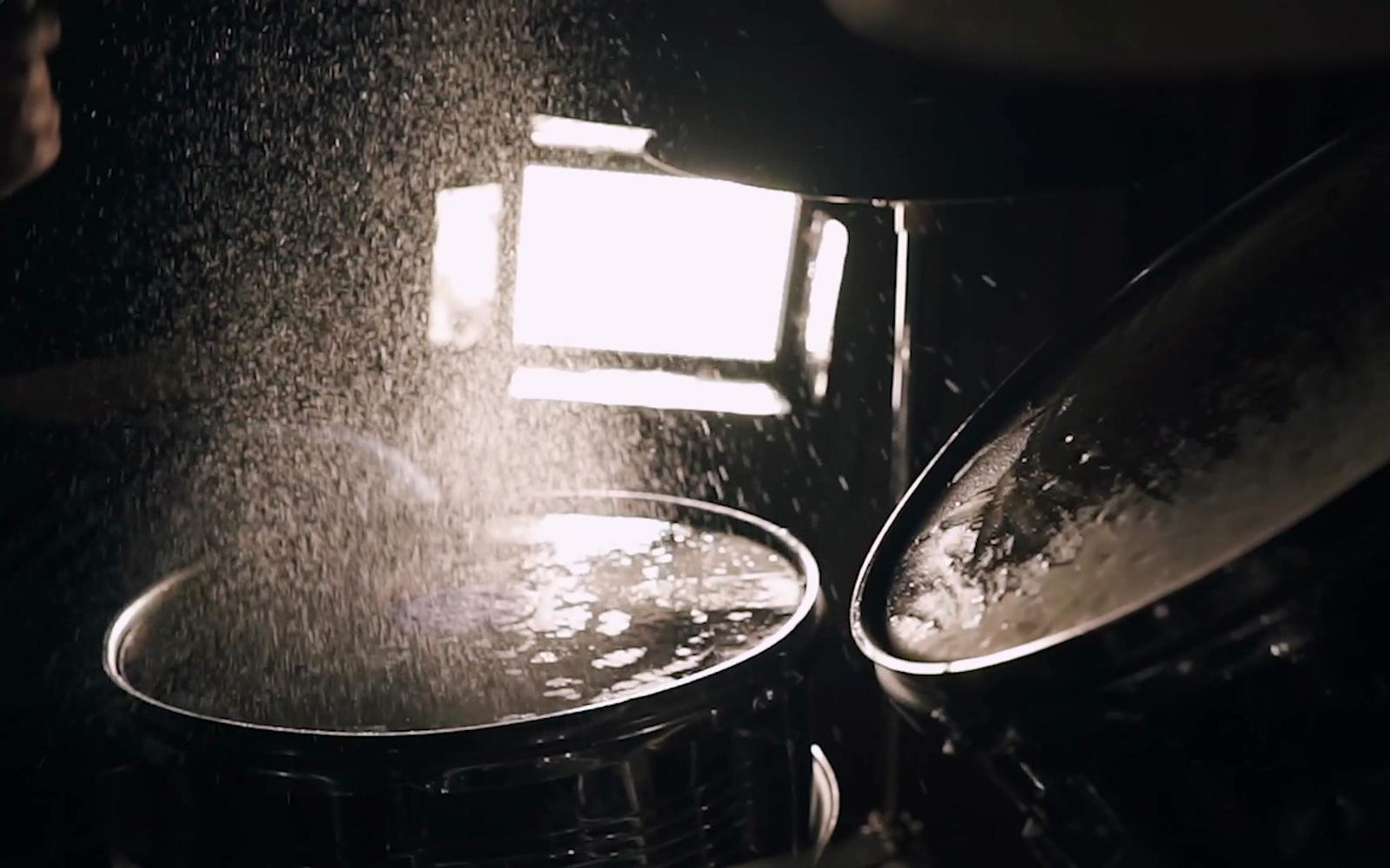 Water spraying off drum heads and a cymbal in a bright backlit close-up