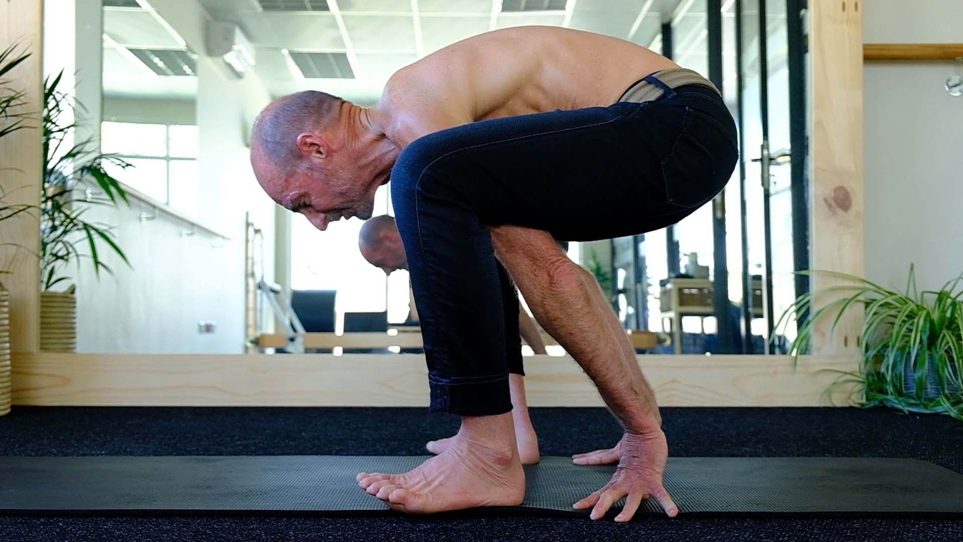 Man folding forward with his hands on the floor in the studio
