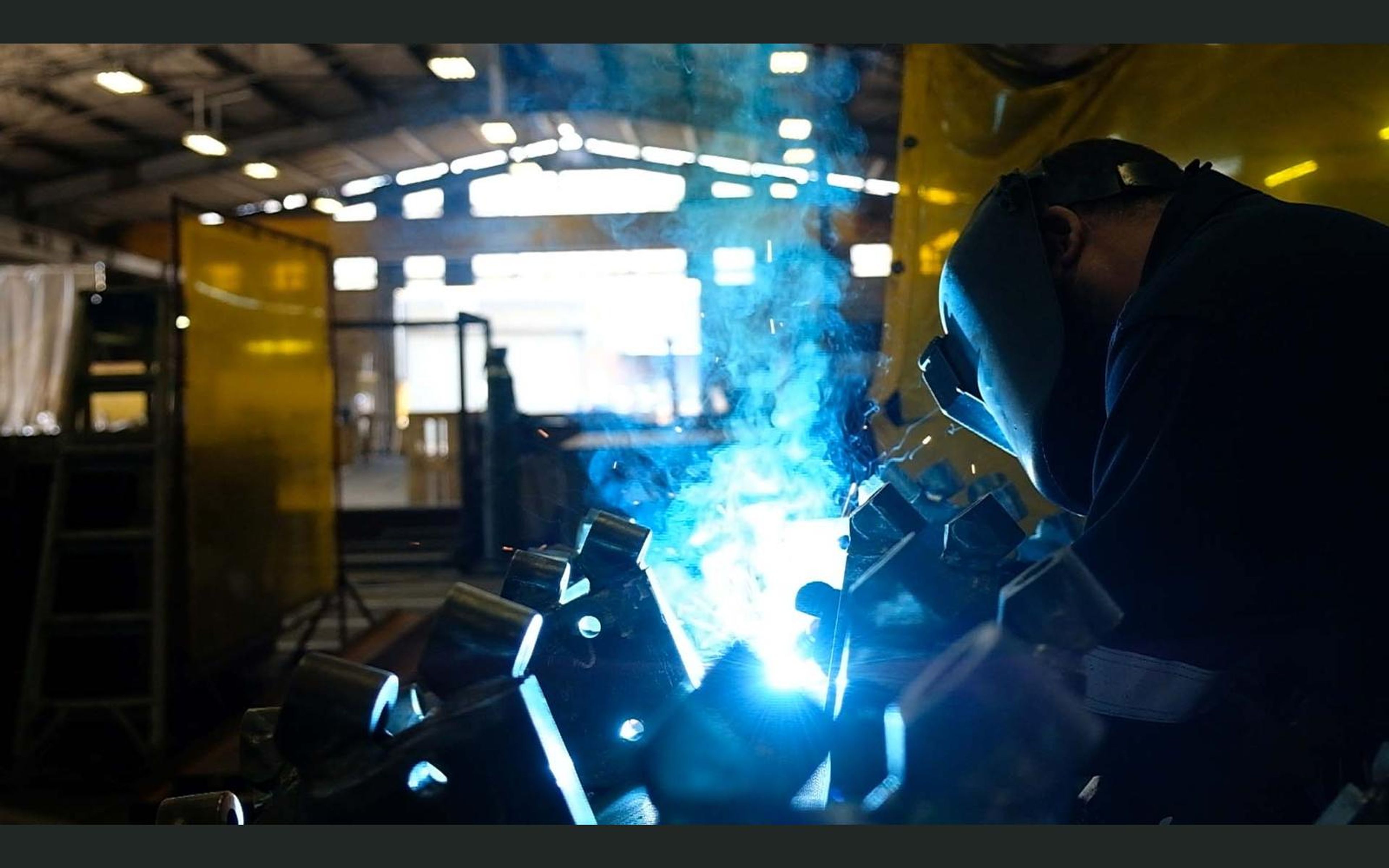Brackets arranged around a drum while a welder works