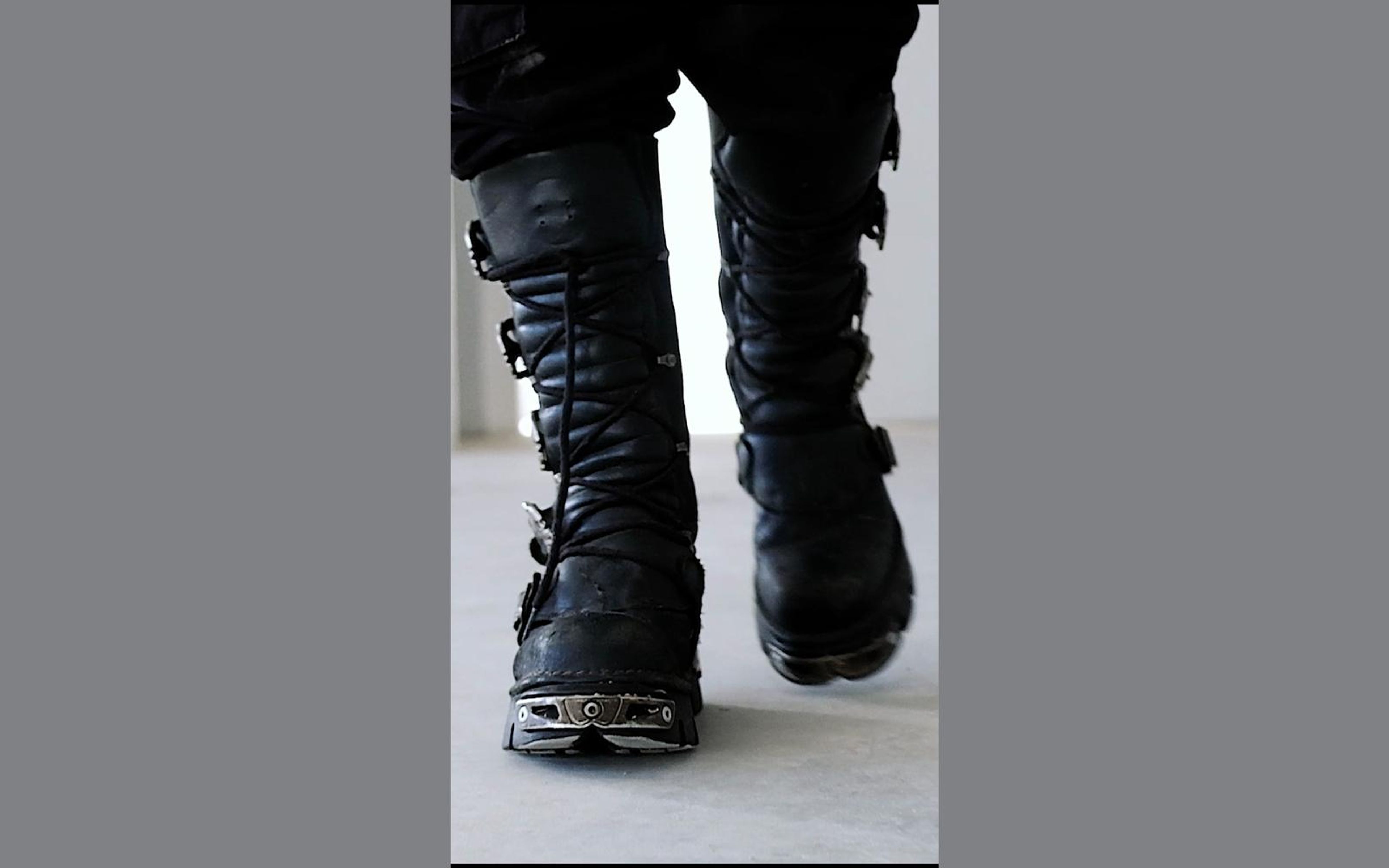 Ground-level view of two heavy black New Rock boots with metal toe plates stepping forward