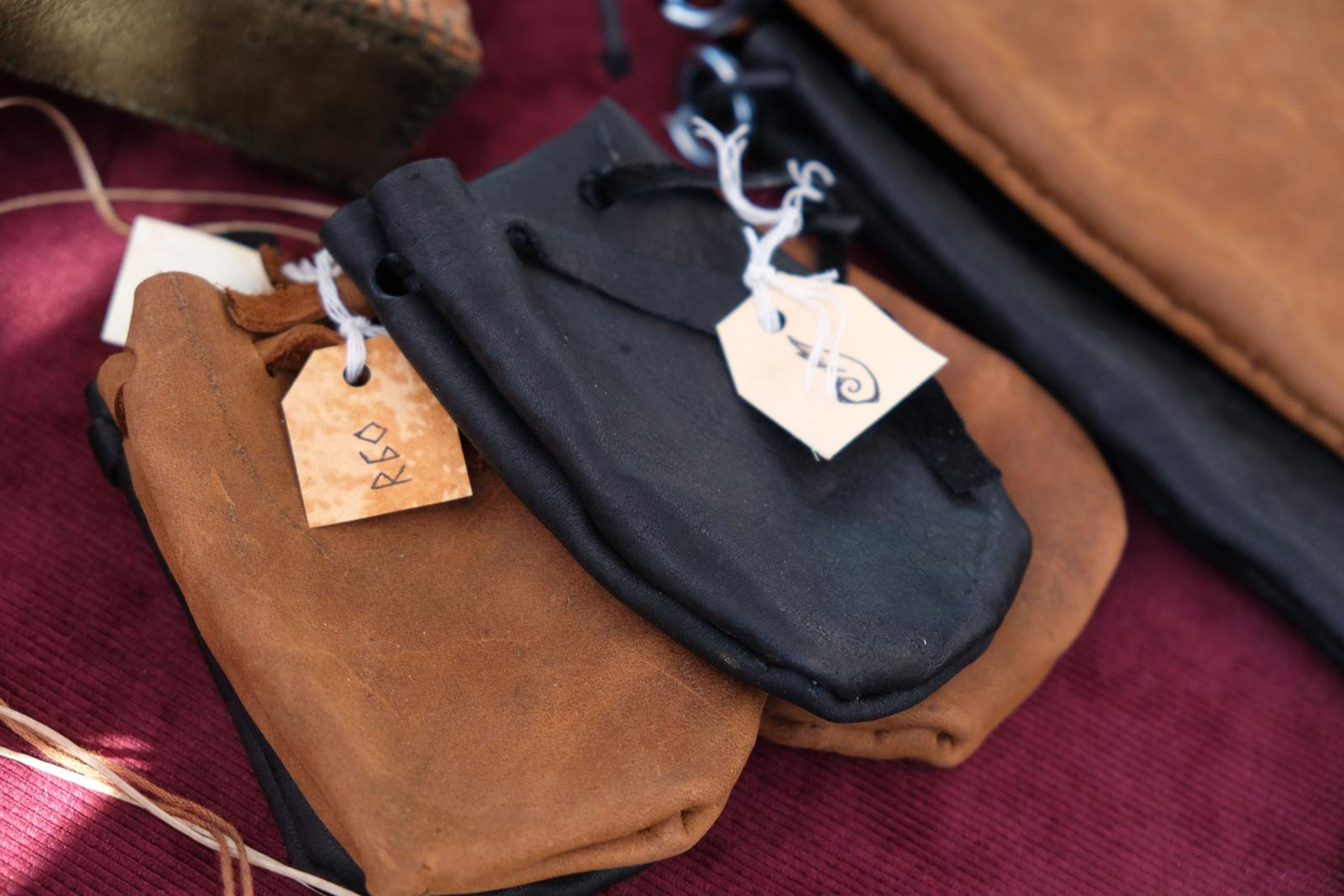 Drawstring leather pouches in tan and black with handwritten tags