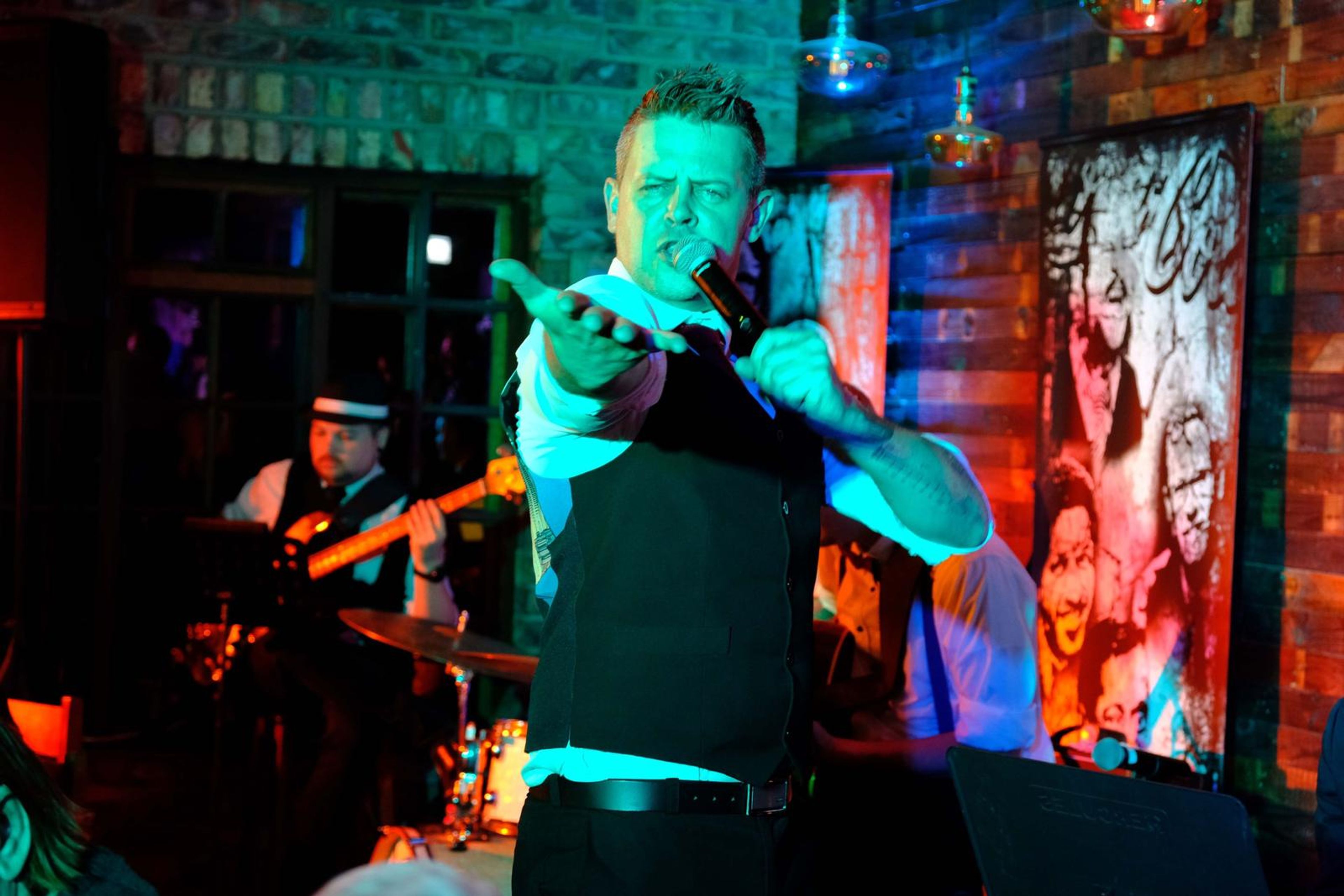 Singer pointing at the camera with the guitarist behind him