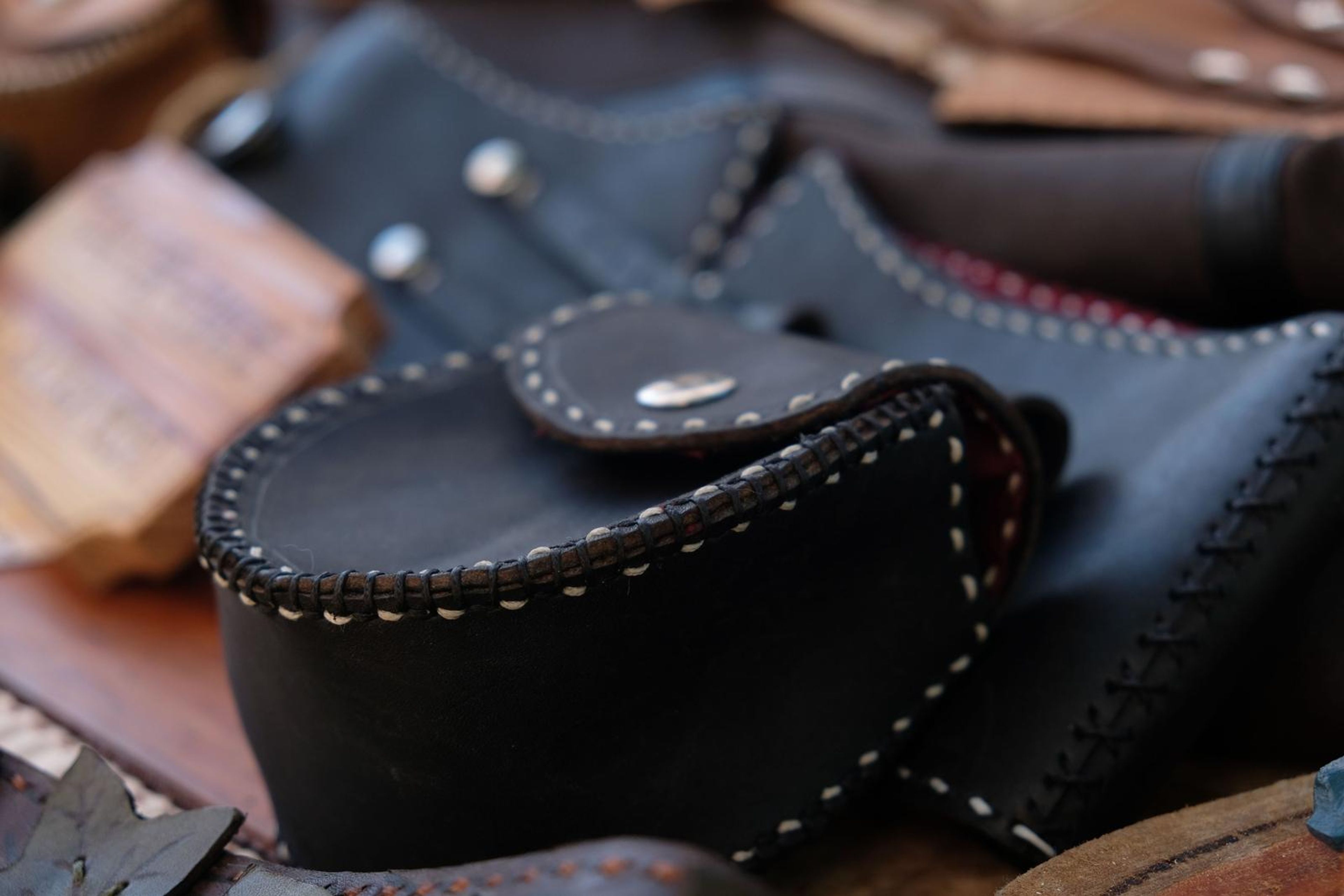 Black leather pouch and corset belts beside a Tailor-Made No Extra Cost sign