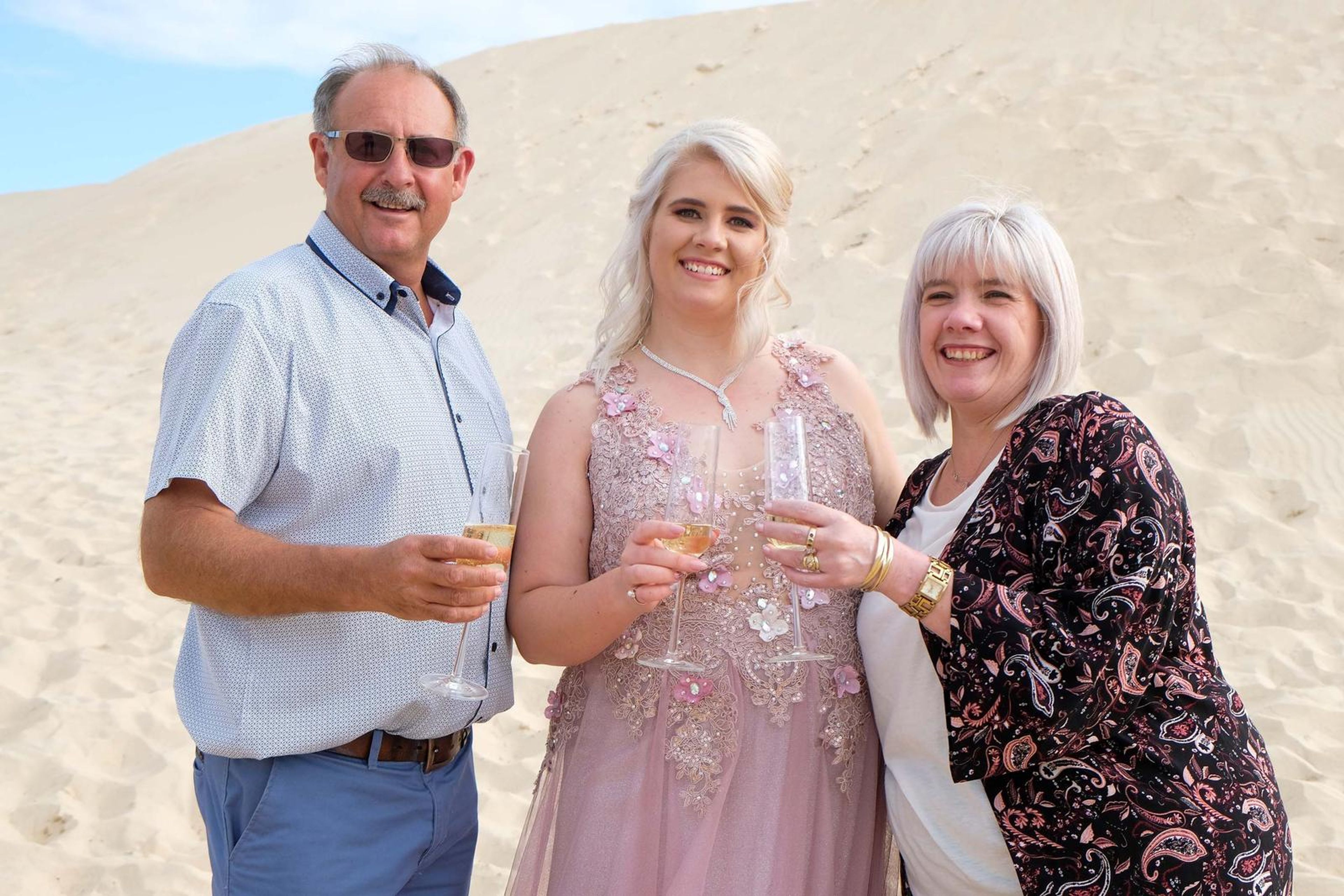 With family on the dunes, holding glasses of champagne