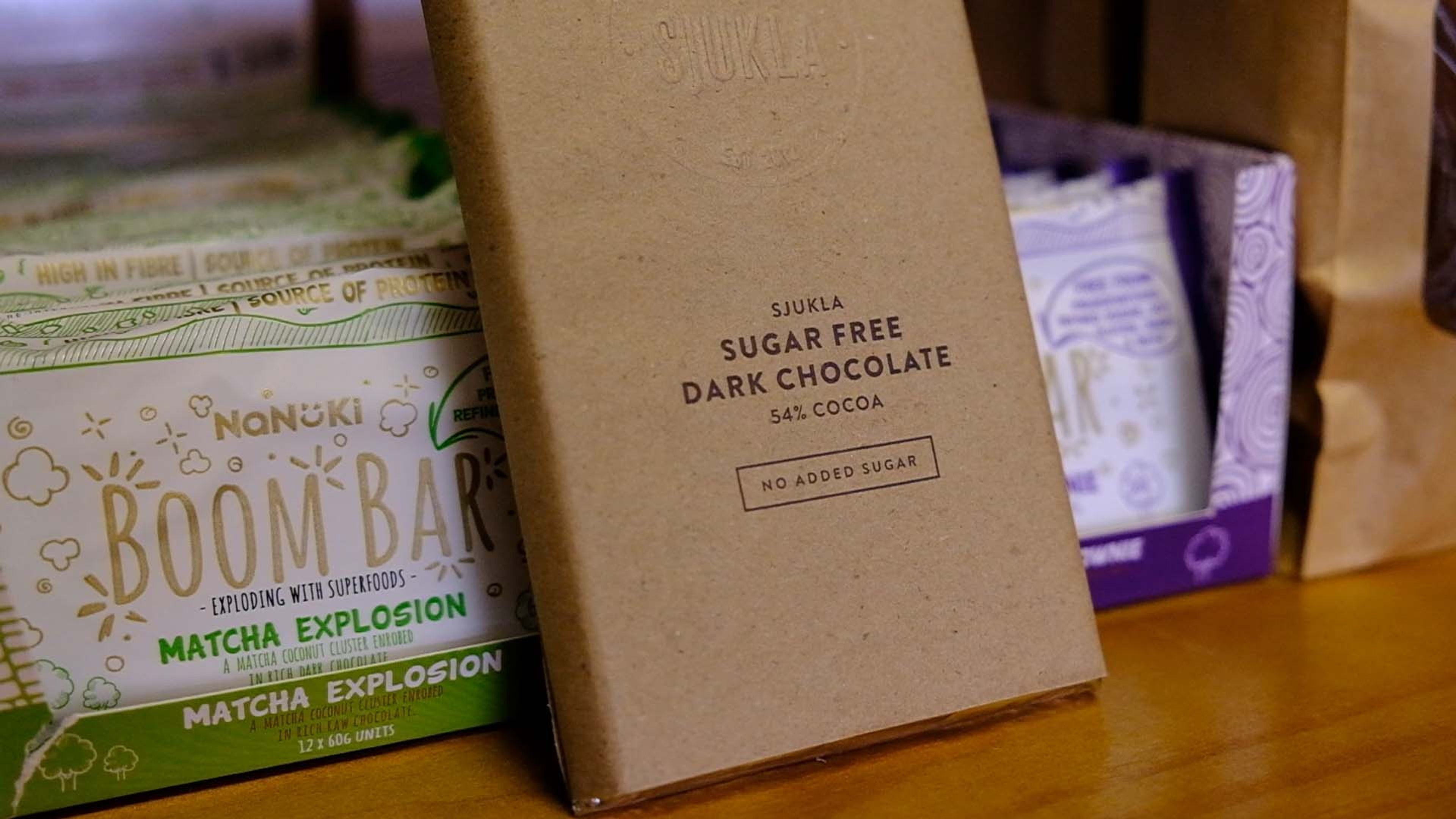 Bars of dark chocolate and snack packs on a wooden shelf