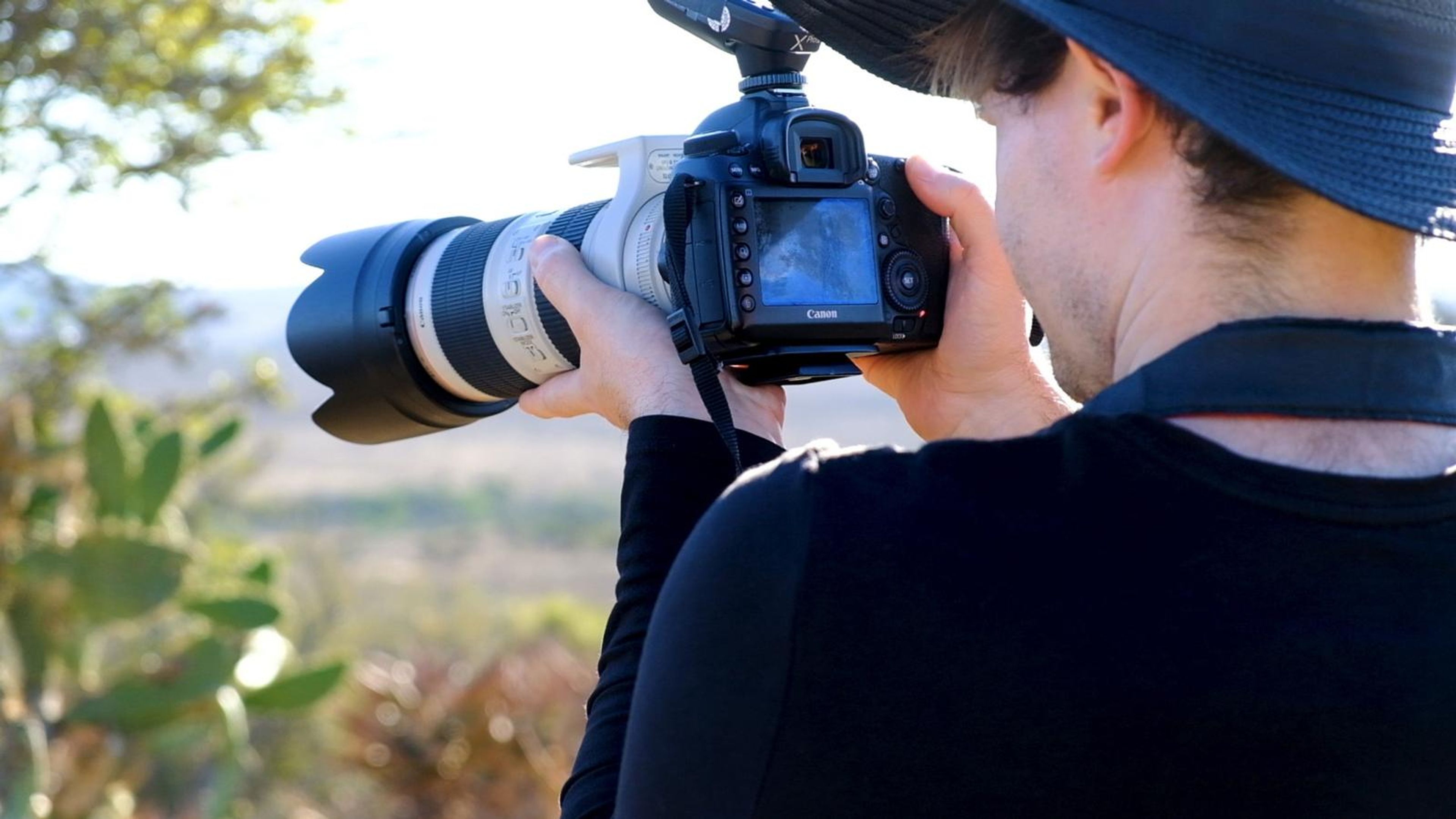 Photographer in a wide-brimmed hat shooting with a long lens