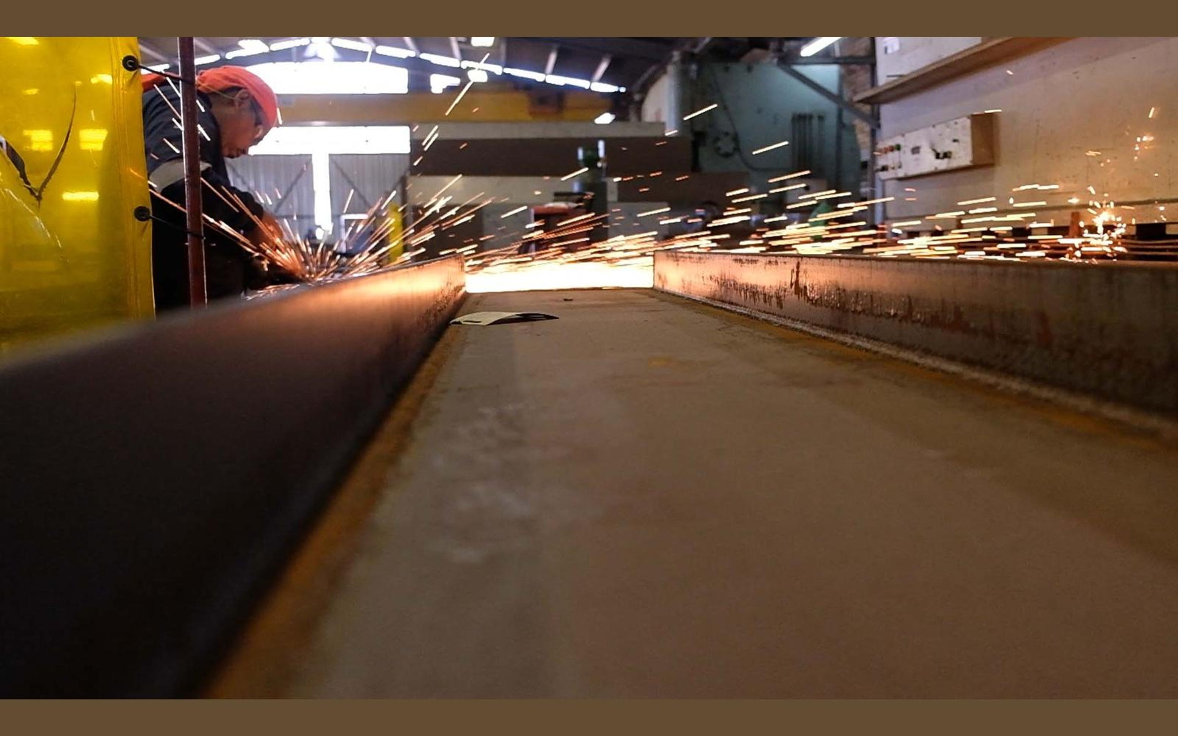 Gloved hands grinding a steel plate