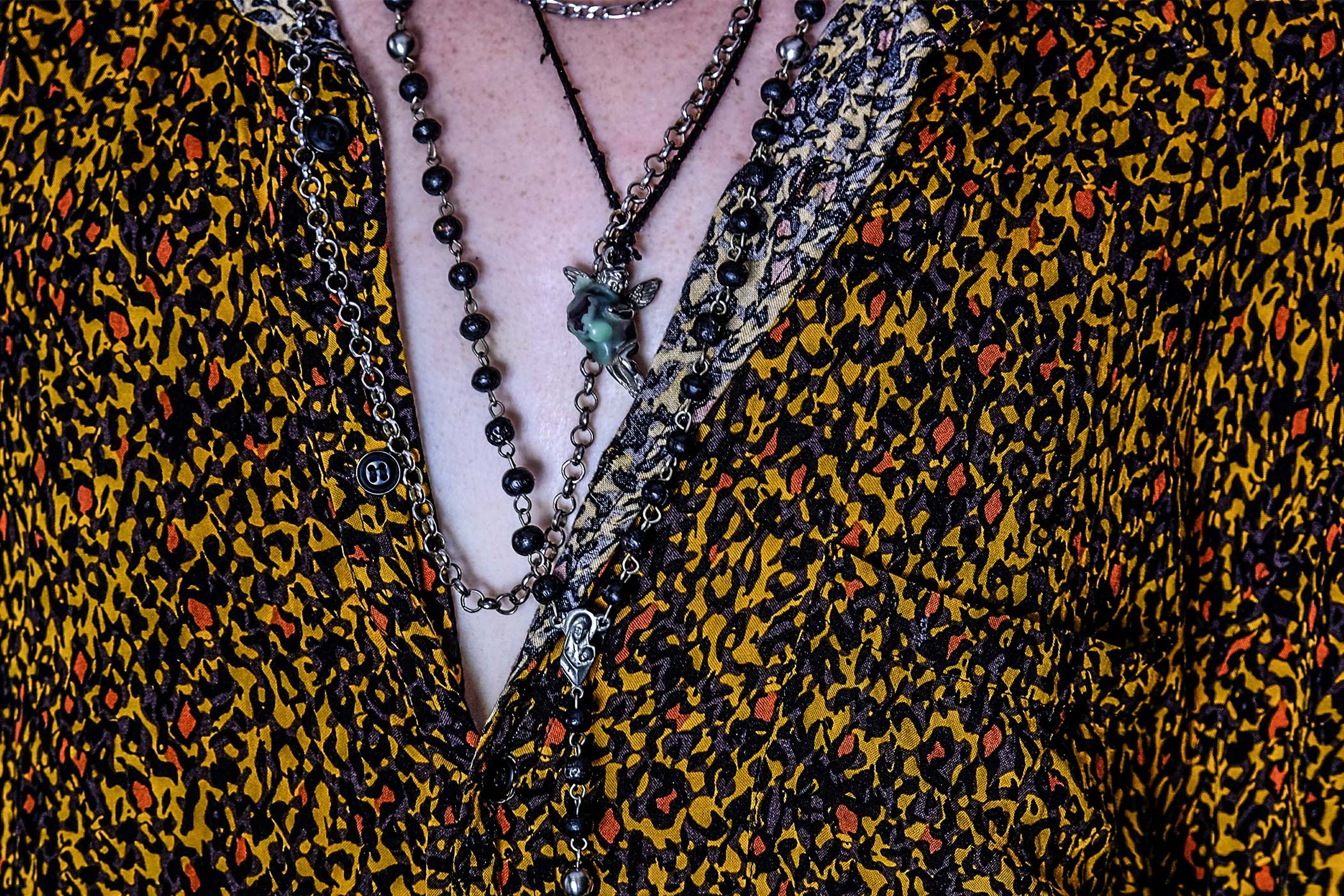 Close-up of layered necklaces against a patterned shirt