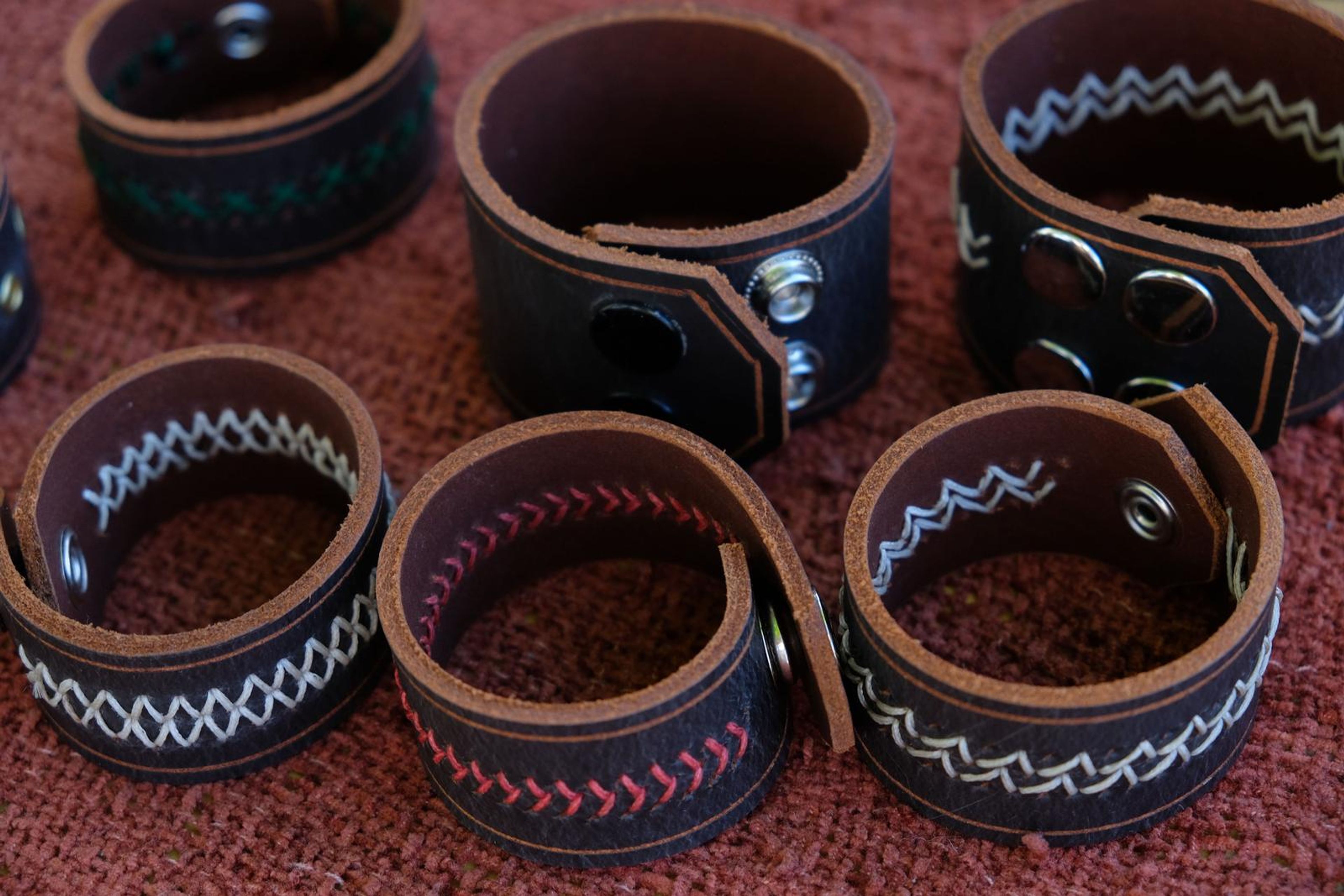Dark leather cuffs with decorative white and red stitching from above