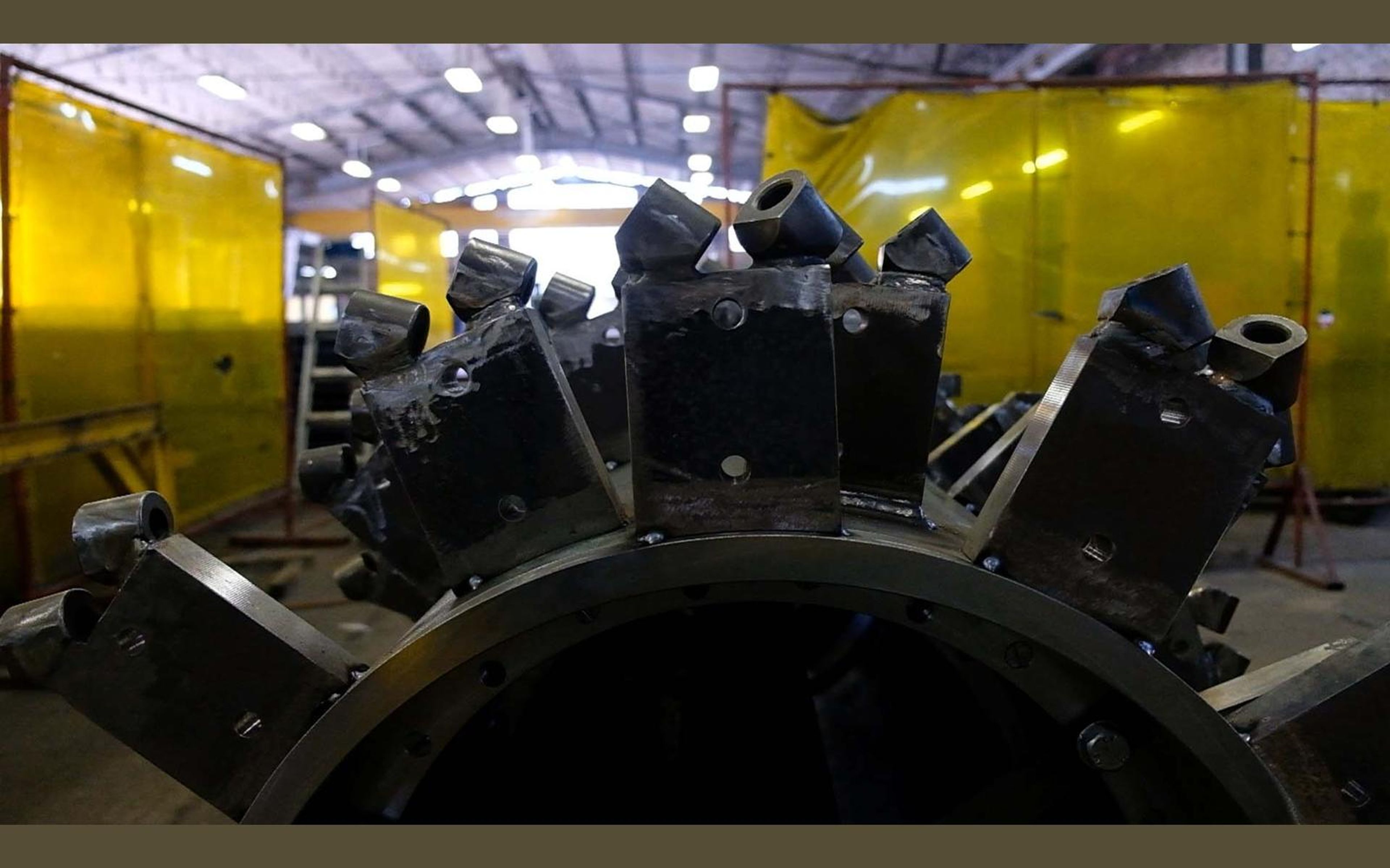 Welder welding steel brackets on a large drum with a bright arc