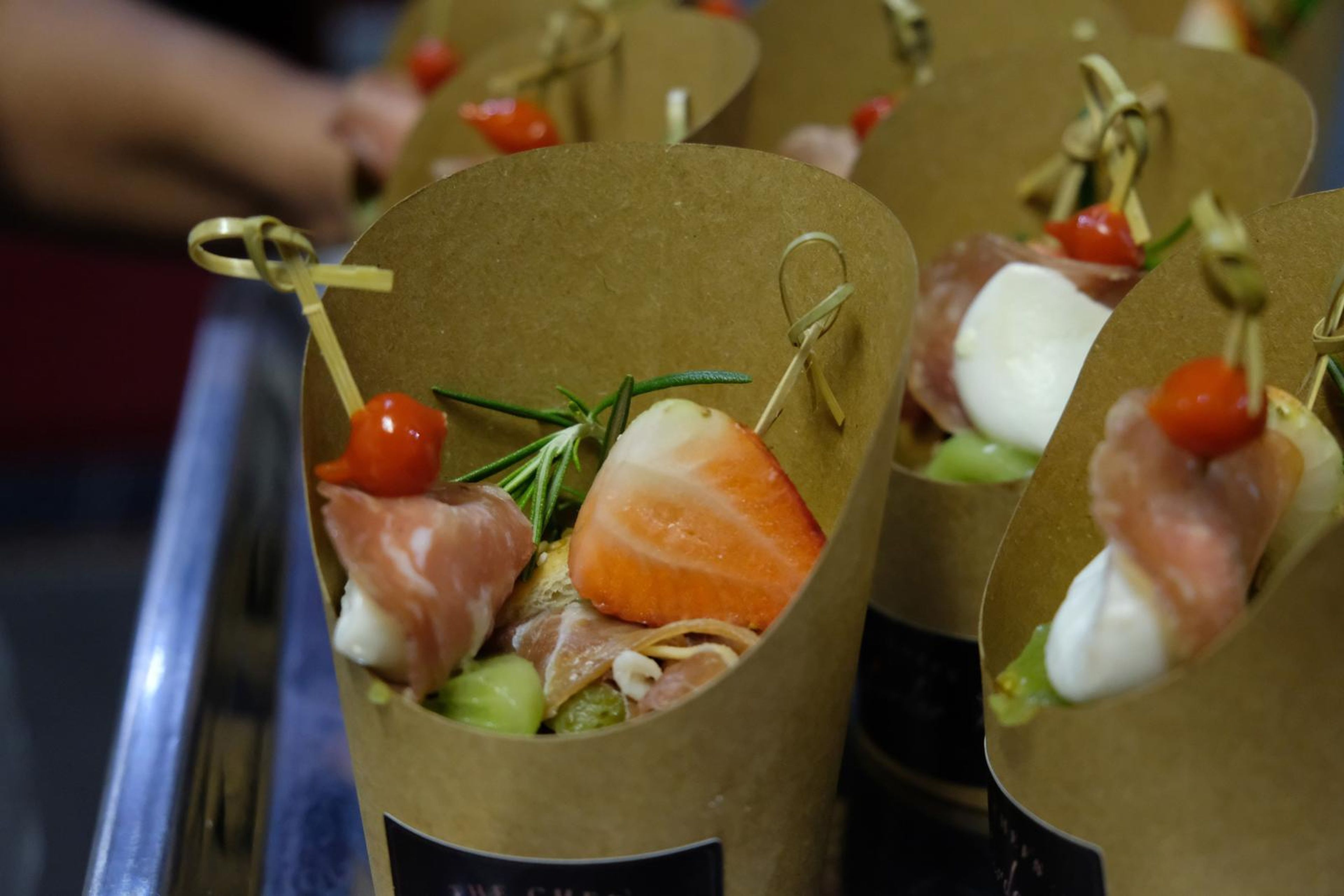 Close-up of canape cones with prosciutto, mozzarella, strawberry and cherry tomato on skewers