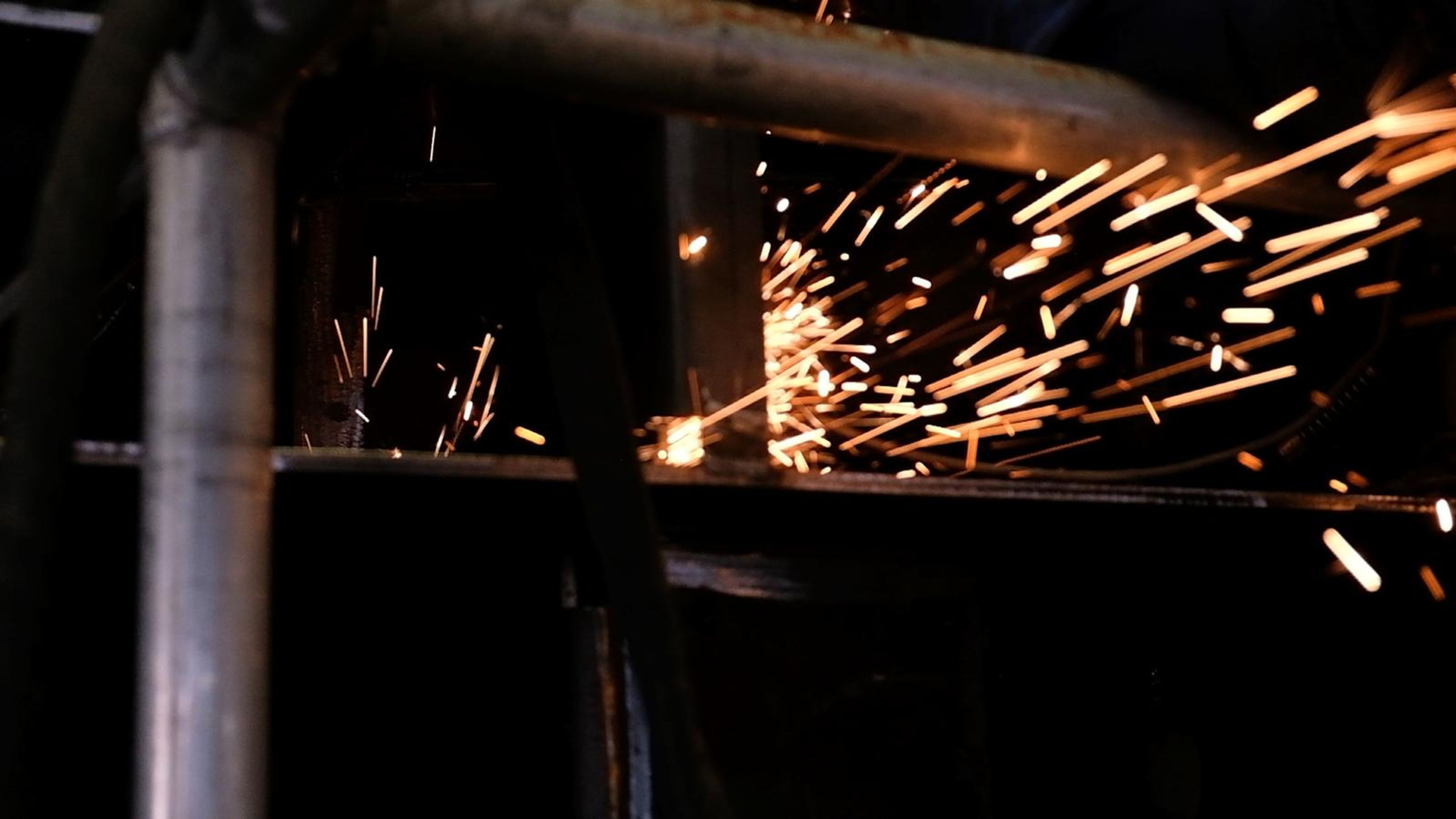Streaks of orange sparks along a steel tube