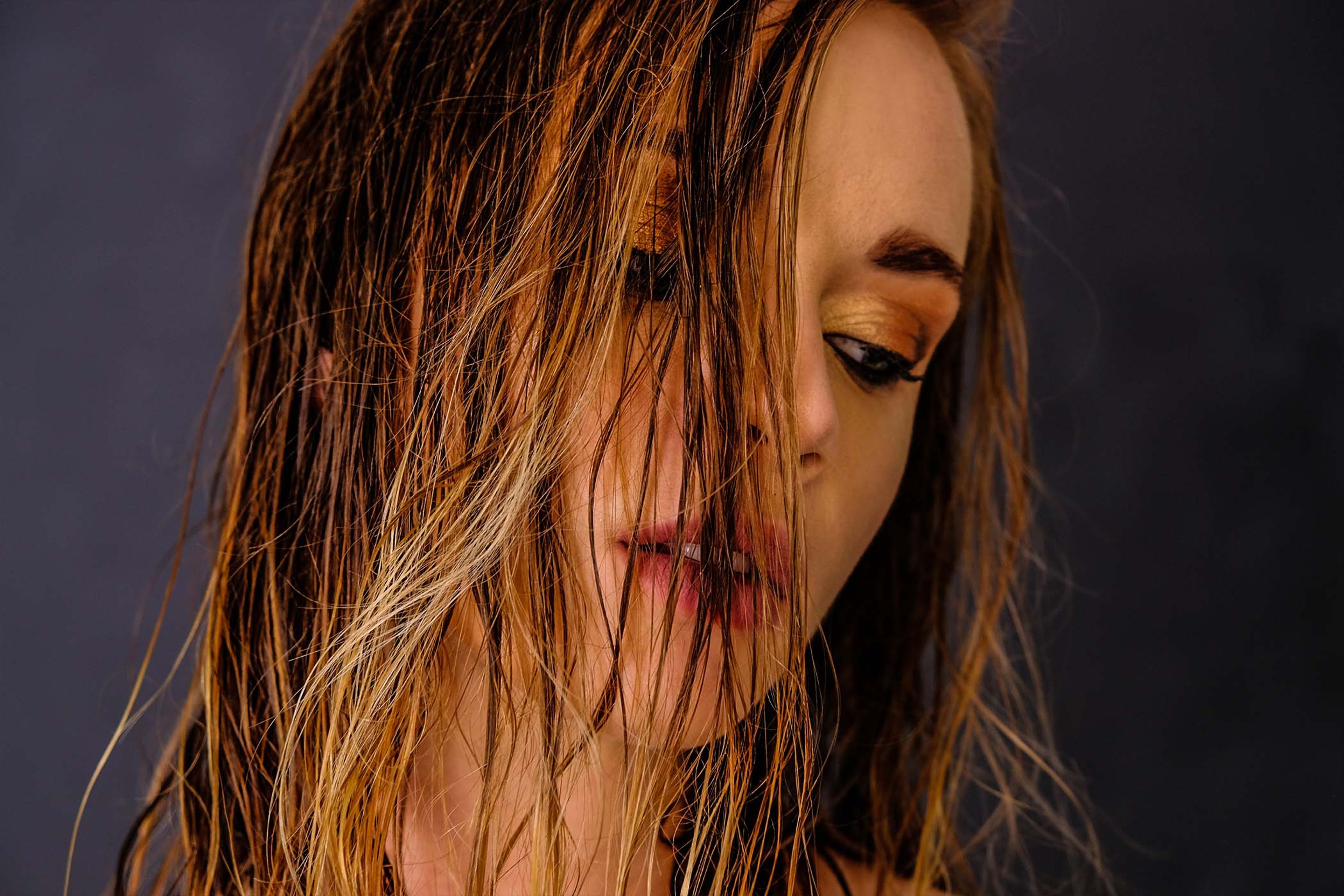 Close-up portrait, wet hair falling across the face, eyes looking down