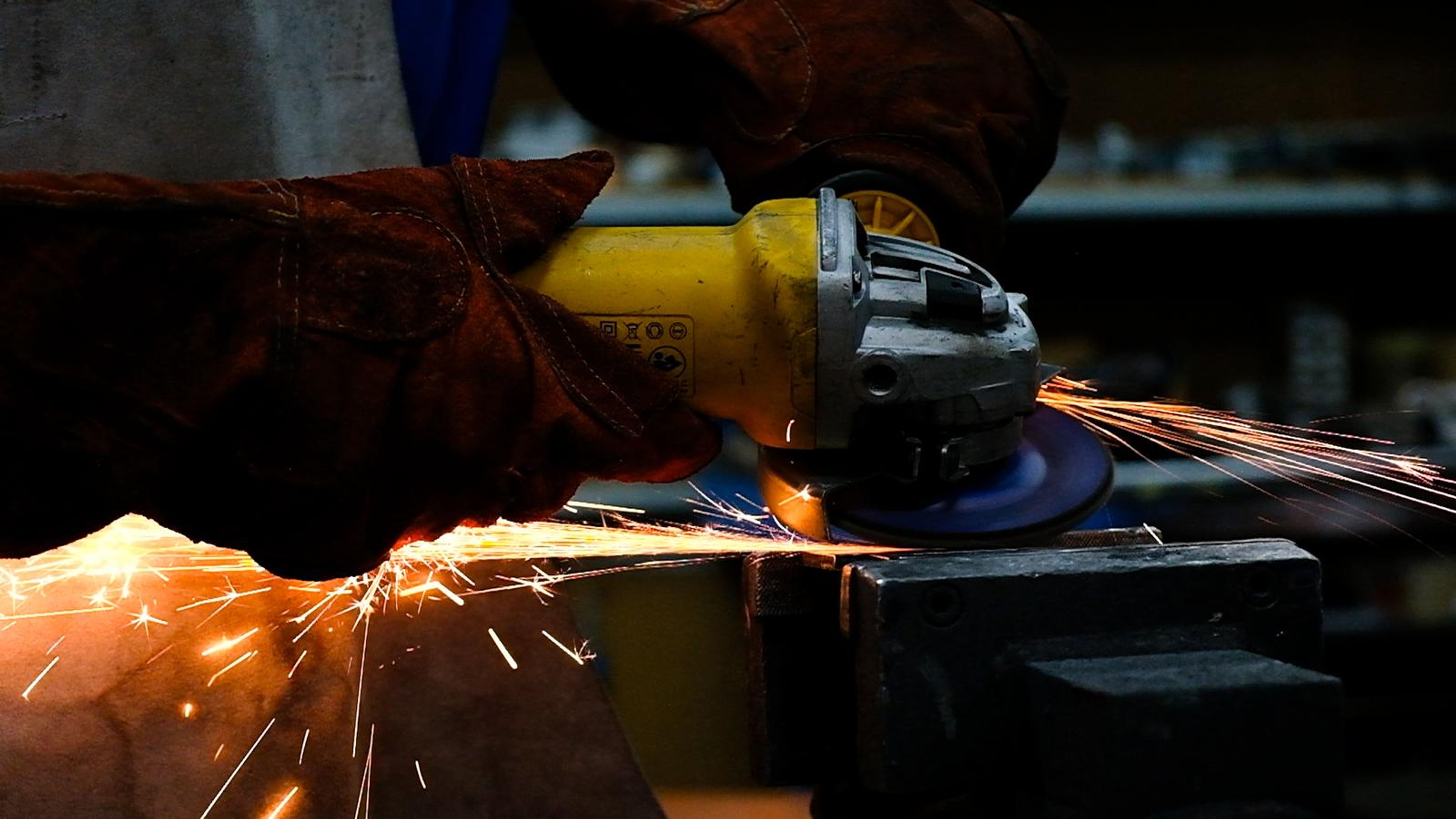 Close view of an angle grinder cutting steel in a dark workshop