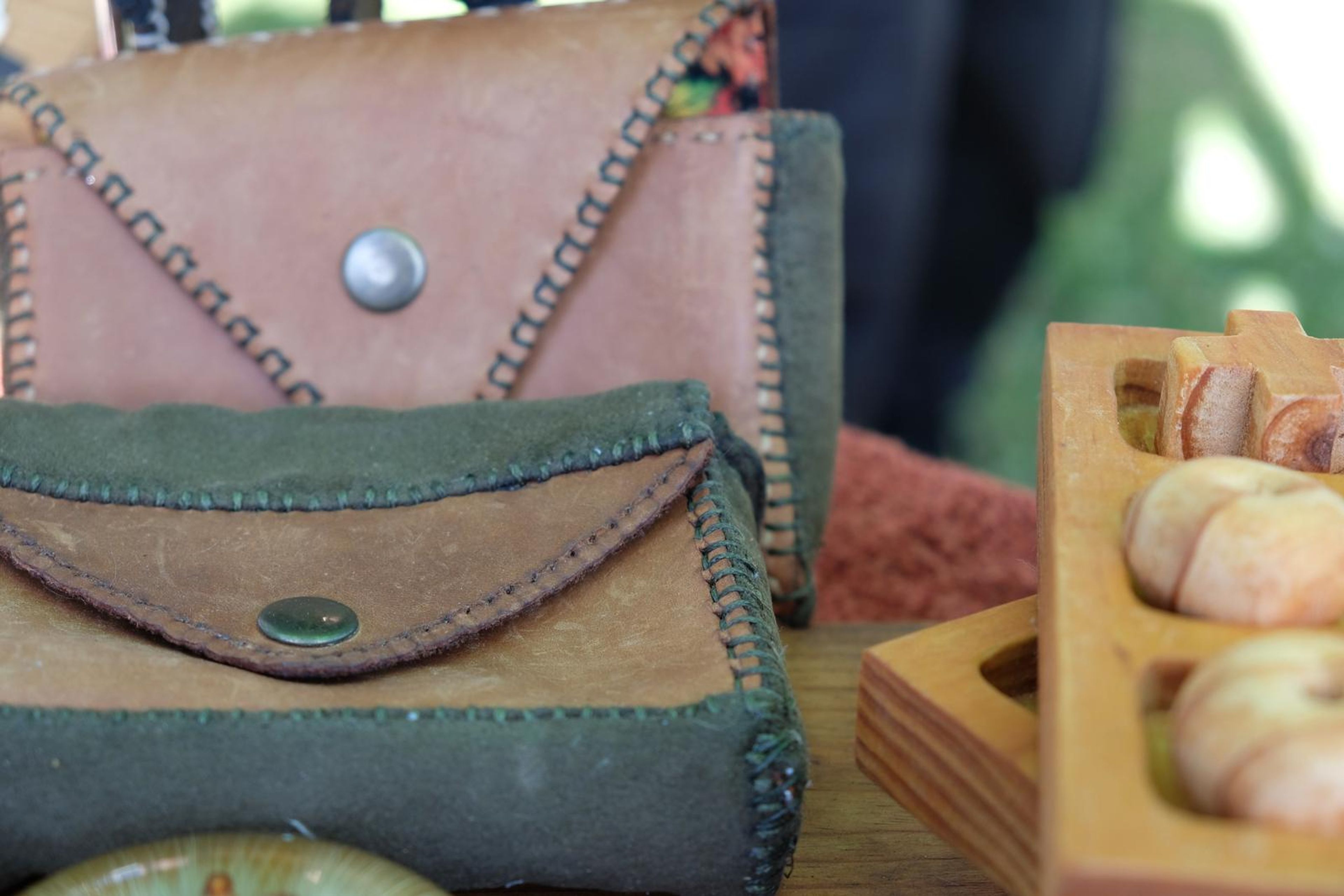 Hand-stitched leather pouches in green and tan with metal studs