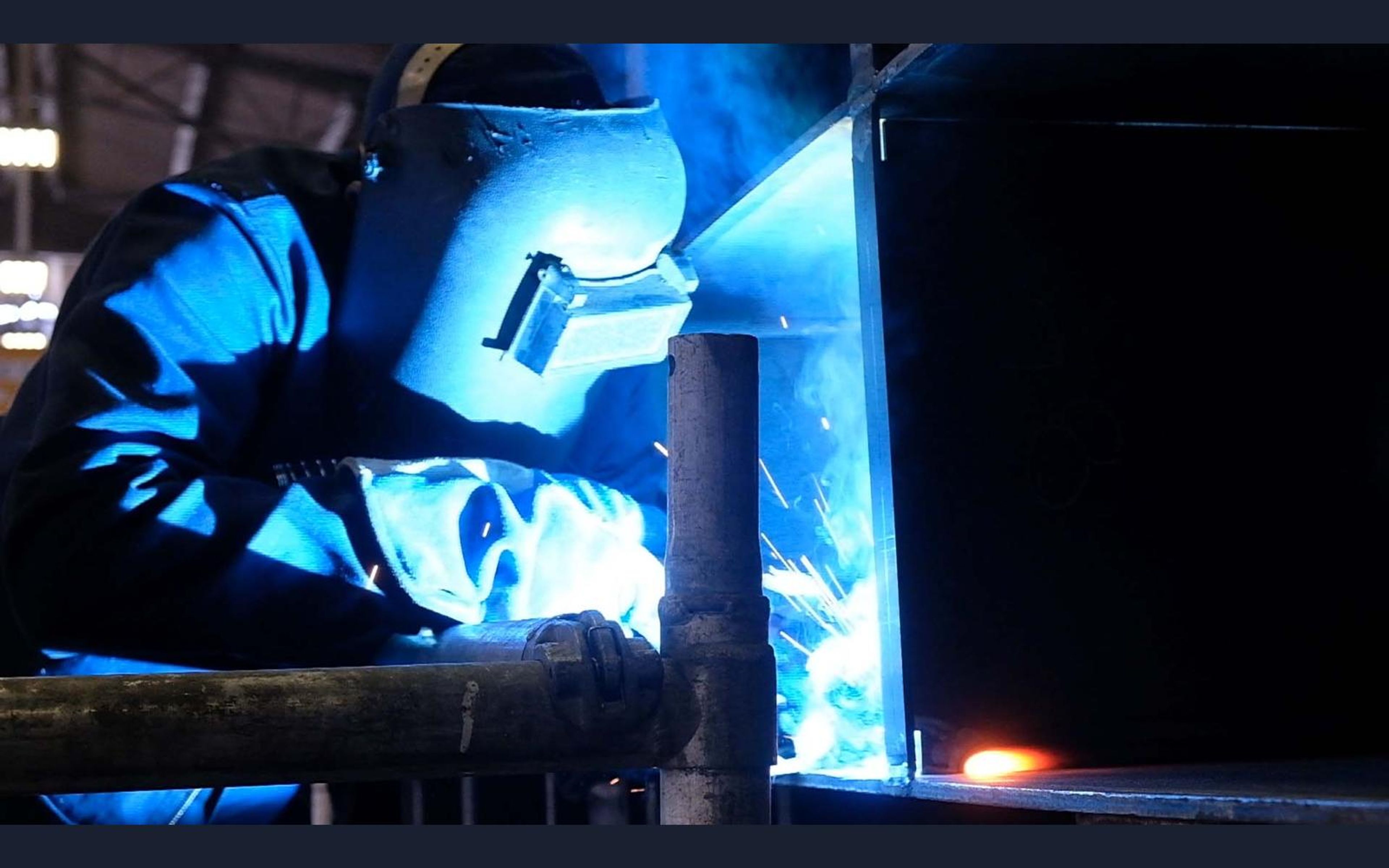 Welder in a mask working in bright blue arc light