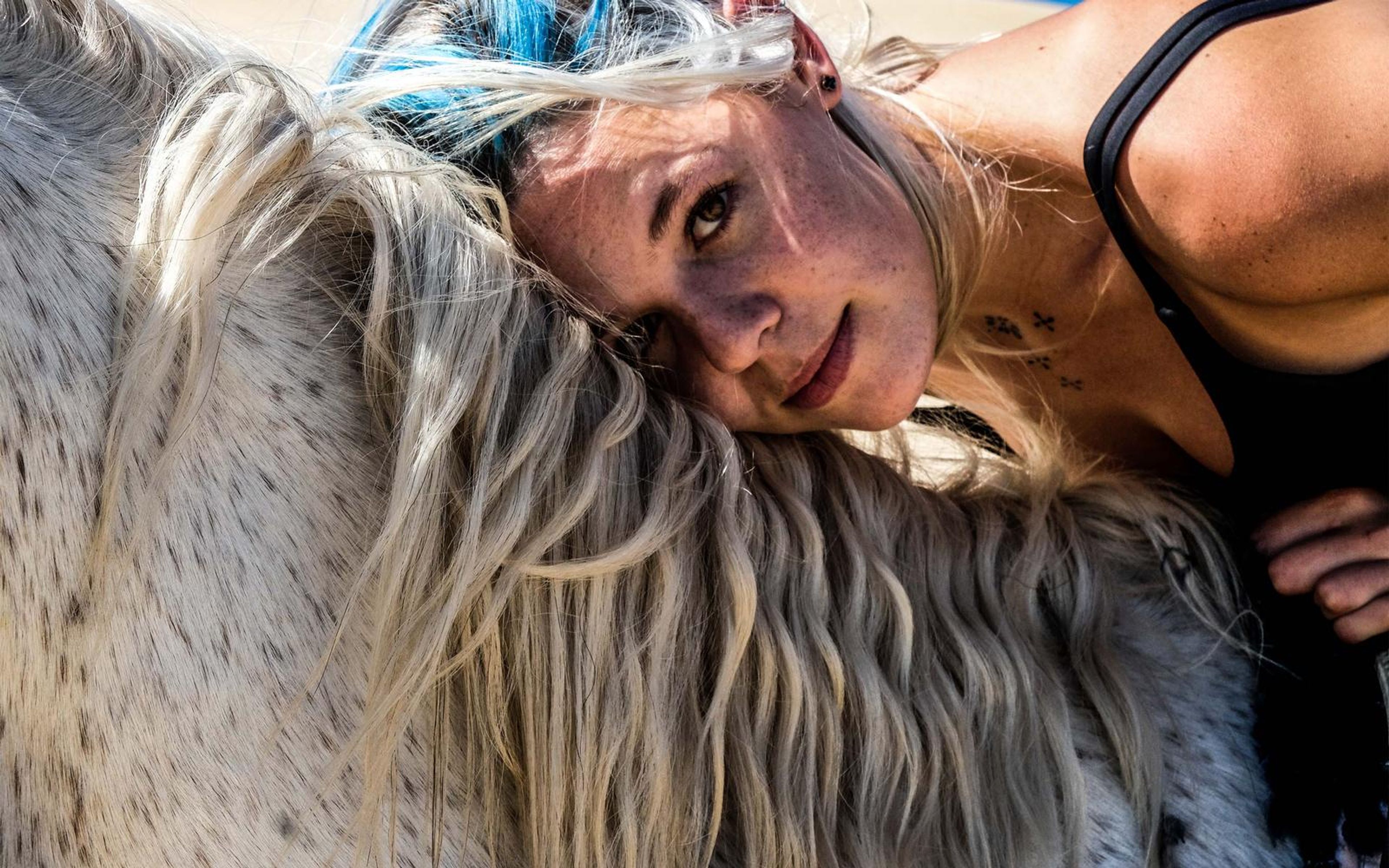 Close portrait of a woman smiling with her head against a horse's mane, soft pastel edit