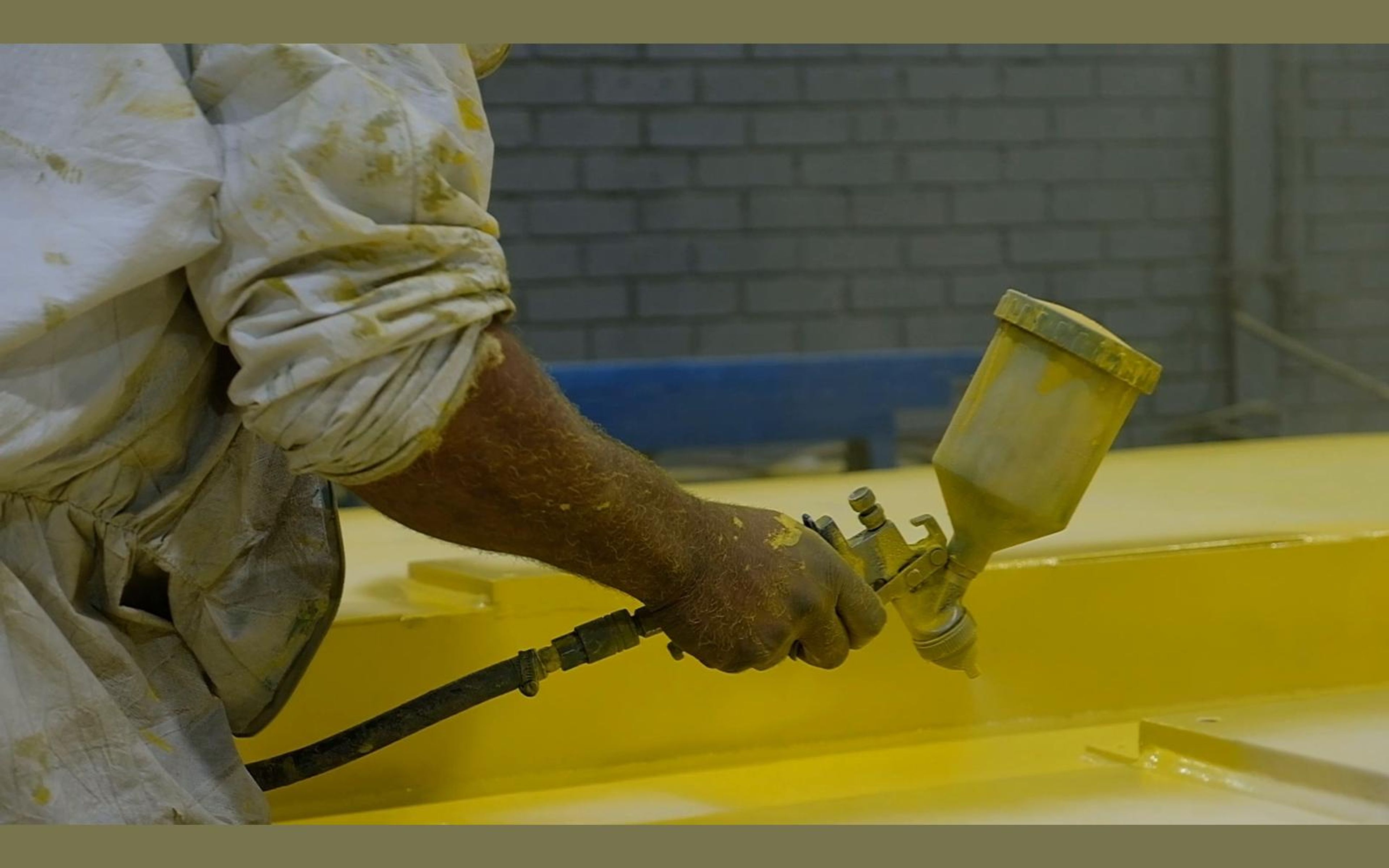 Spray gun with a cup of yellow paint