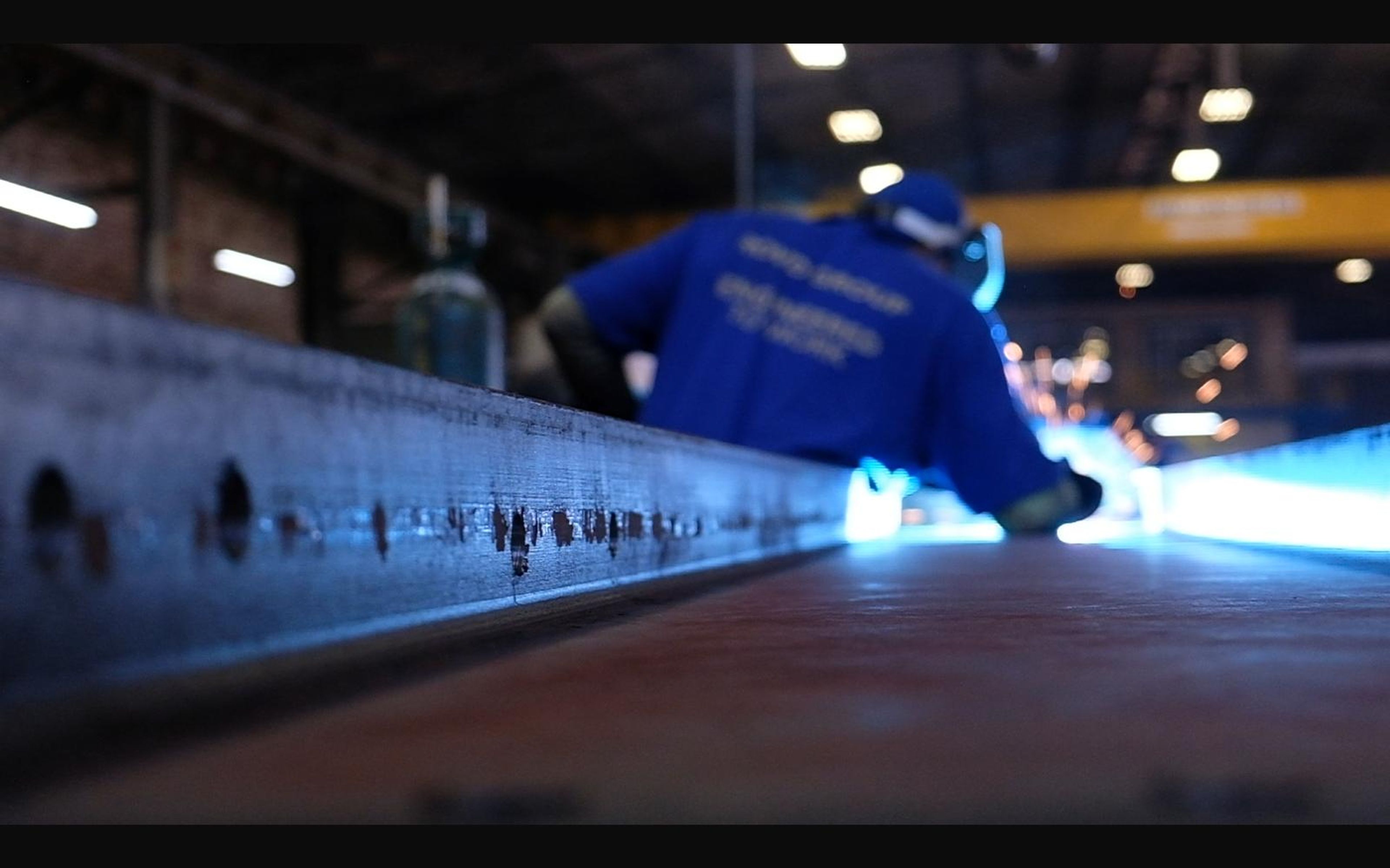 Welder working along a long steel beam