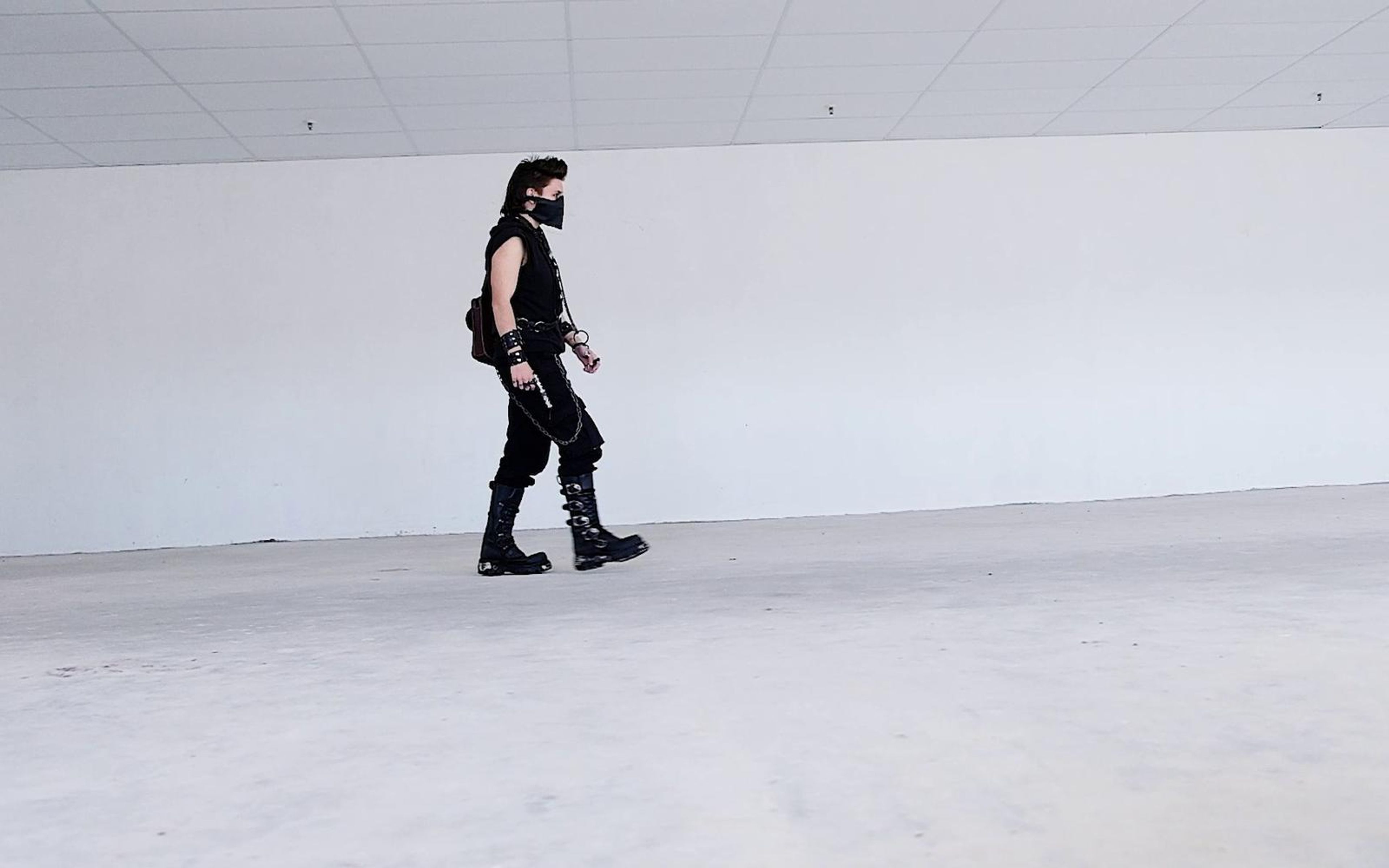 Warrior walking across the far side of a large white room, small in a wide frame