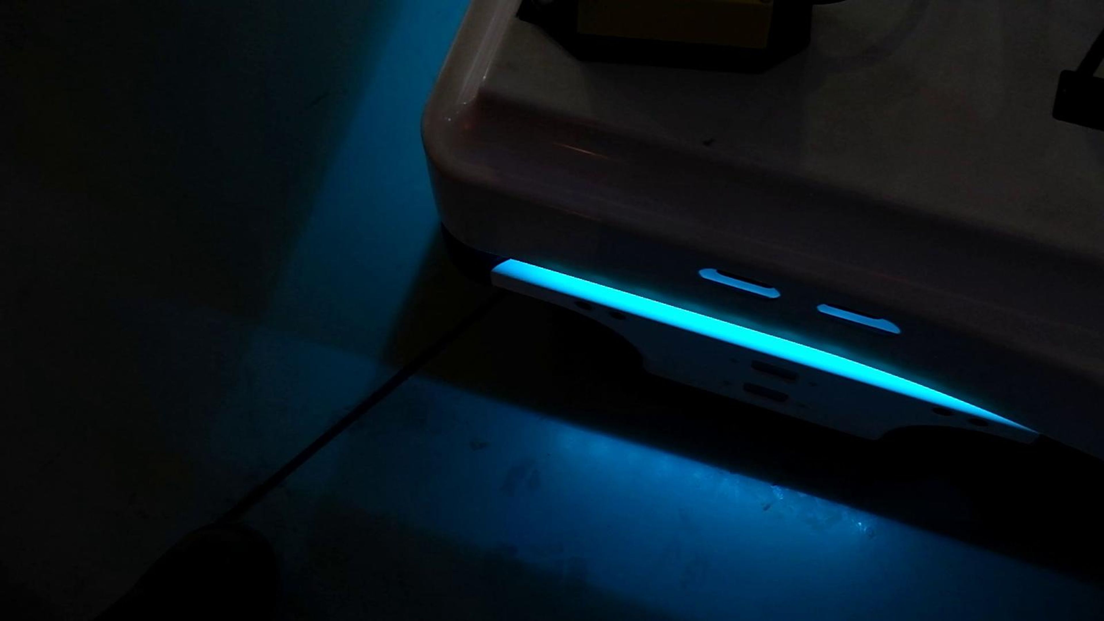 Glowing cyan light strip of an autonomous robot on the floor