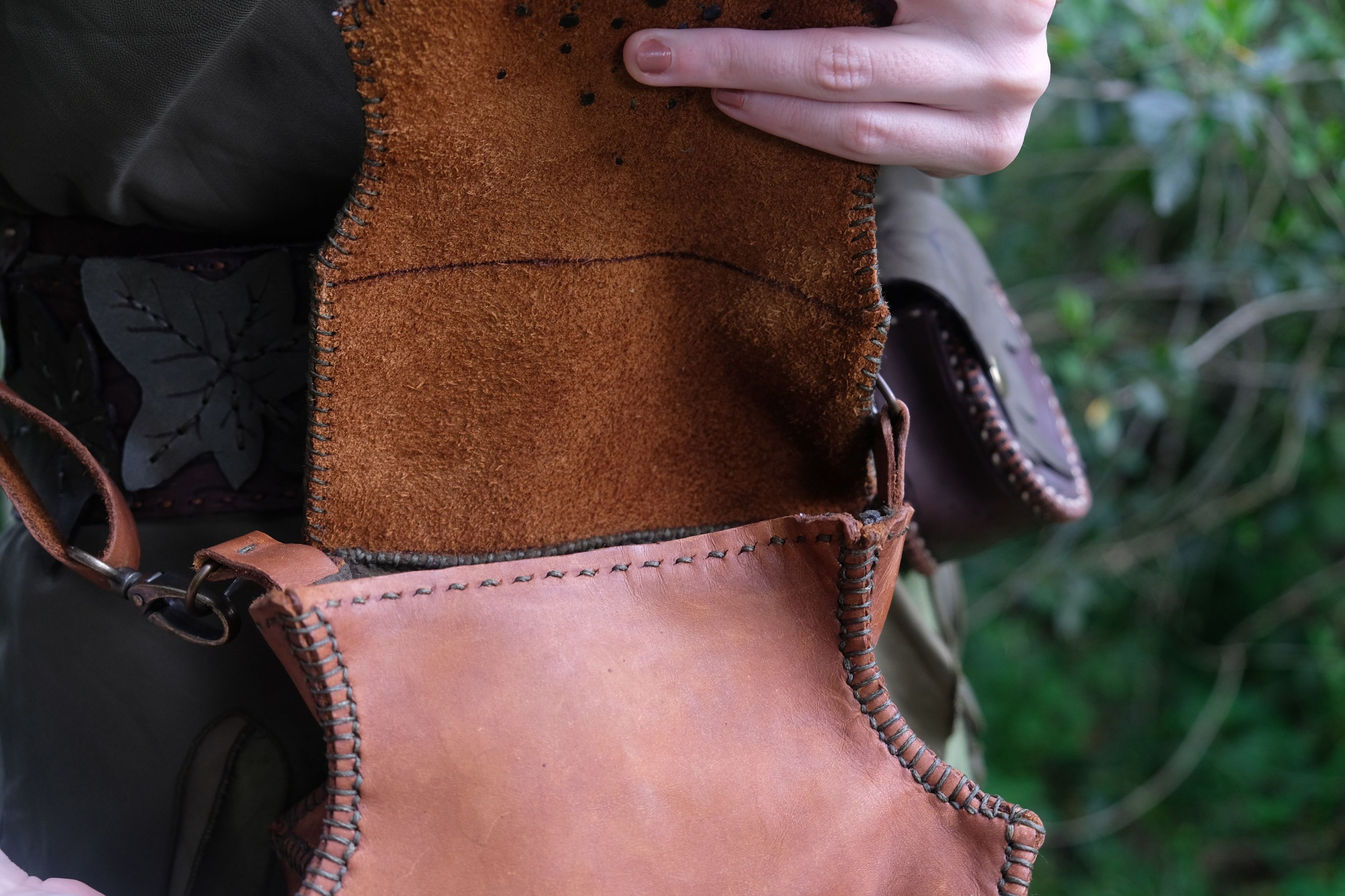 Open tan leather bag with a leaf-shaped flap and a shoulder strap