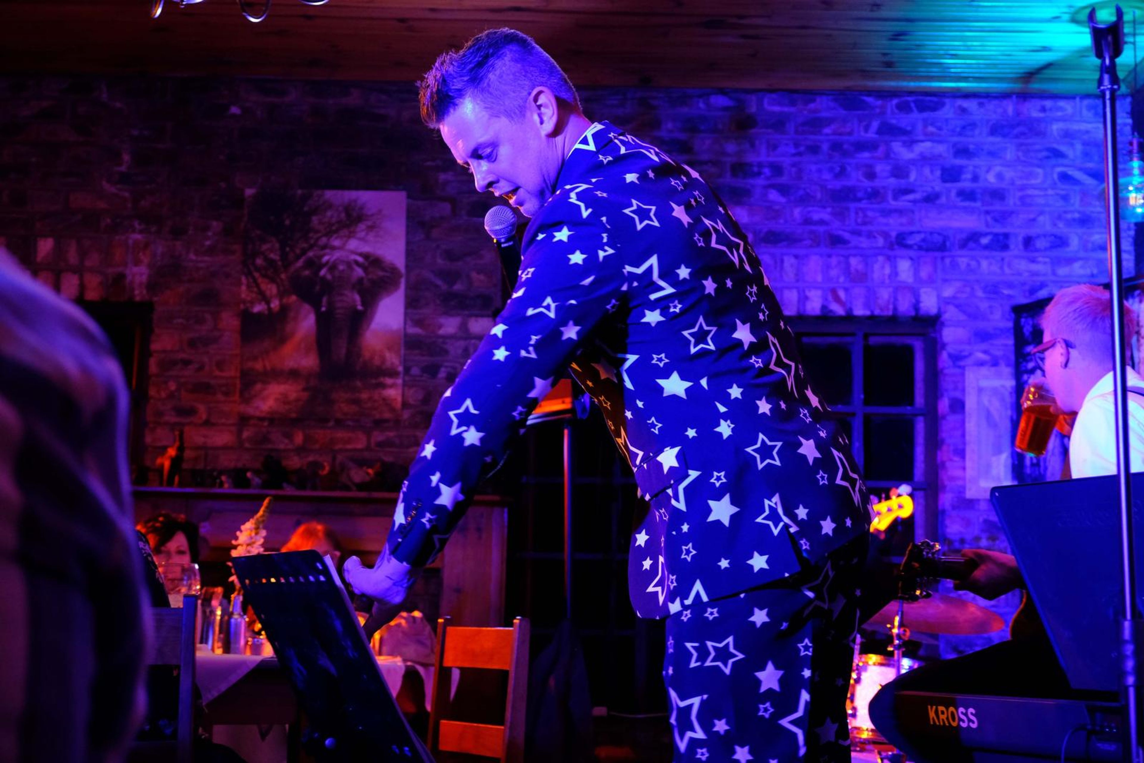 Singer in a star-patterned suit leaning over the keyboard