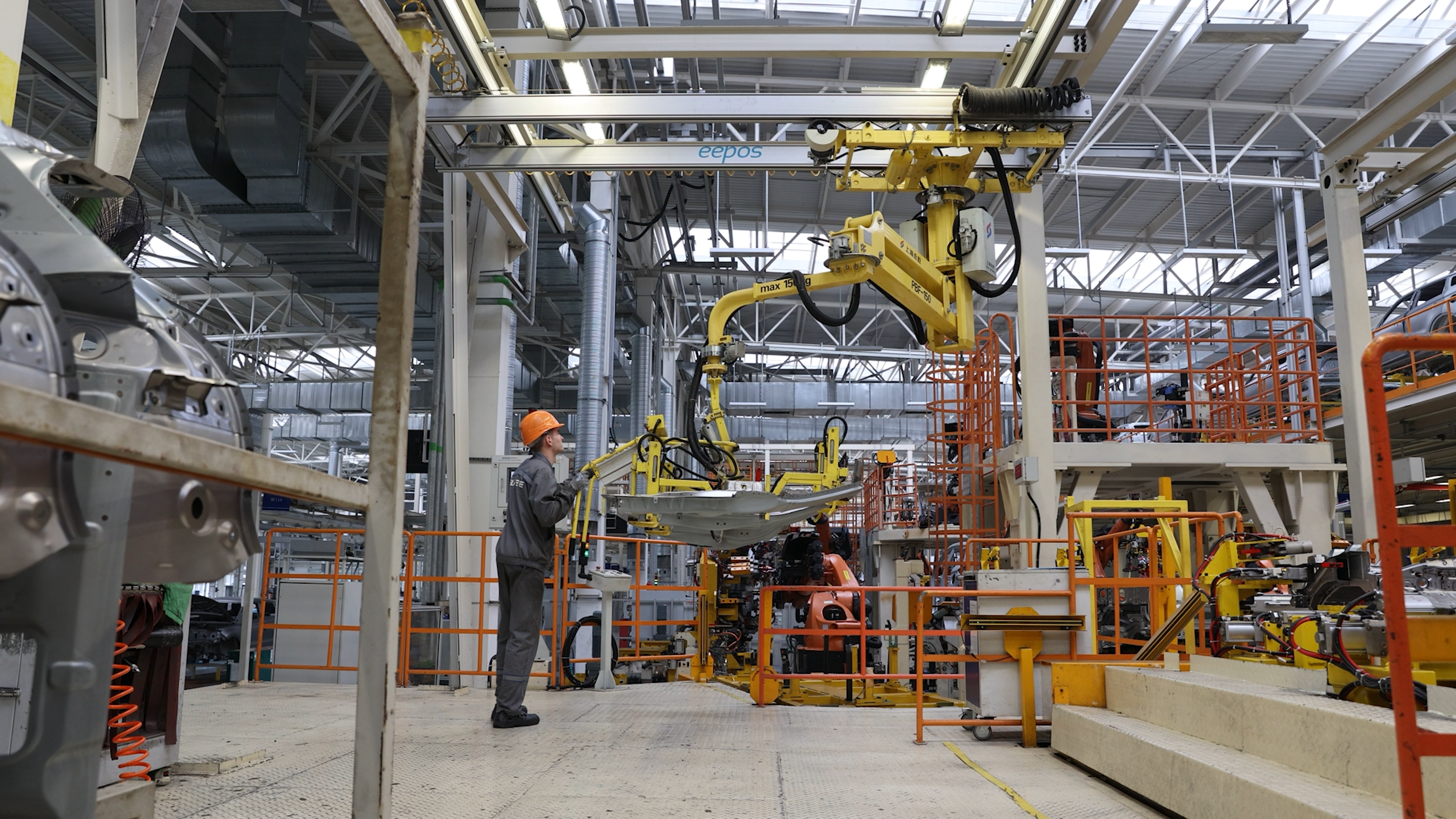 Worker in an automotive assembly plant beneath overhead lifting equipment