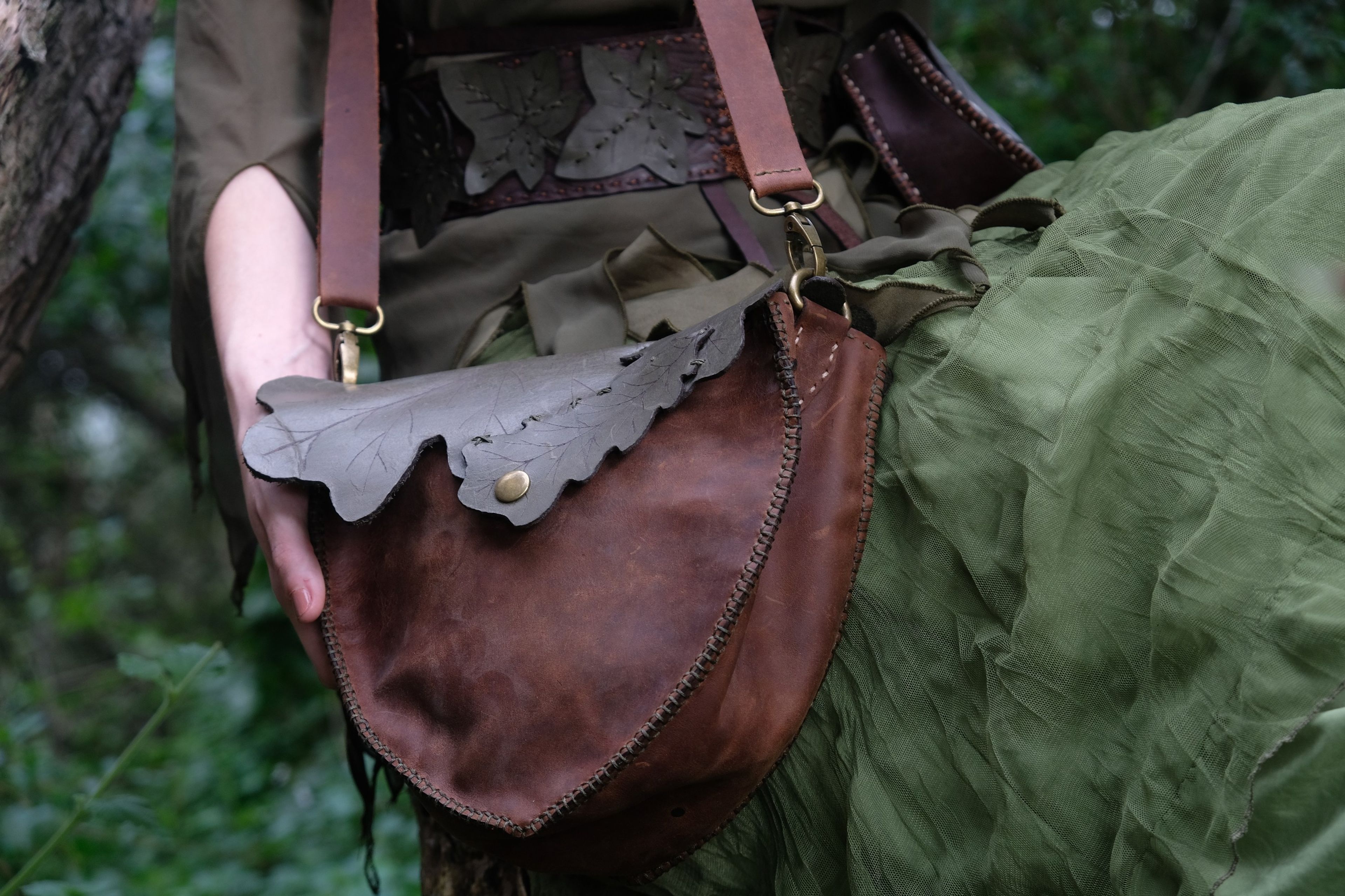 Brown leather bag with a leaf flap against a green skirt