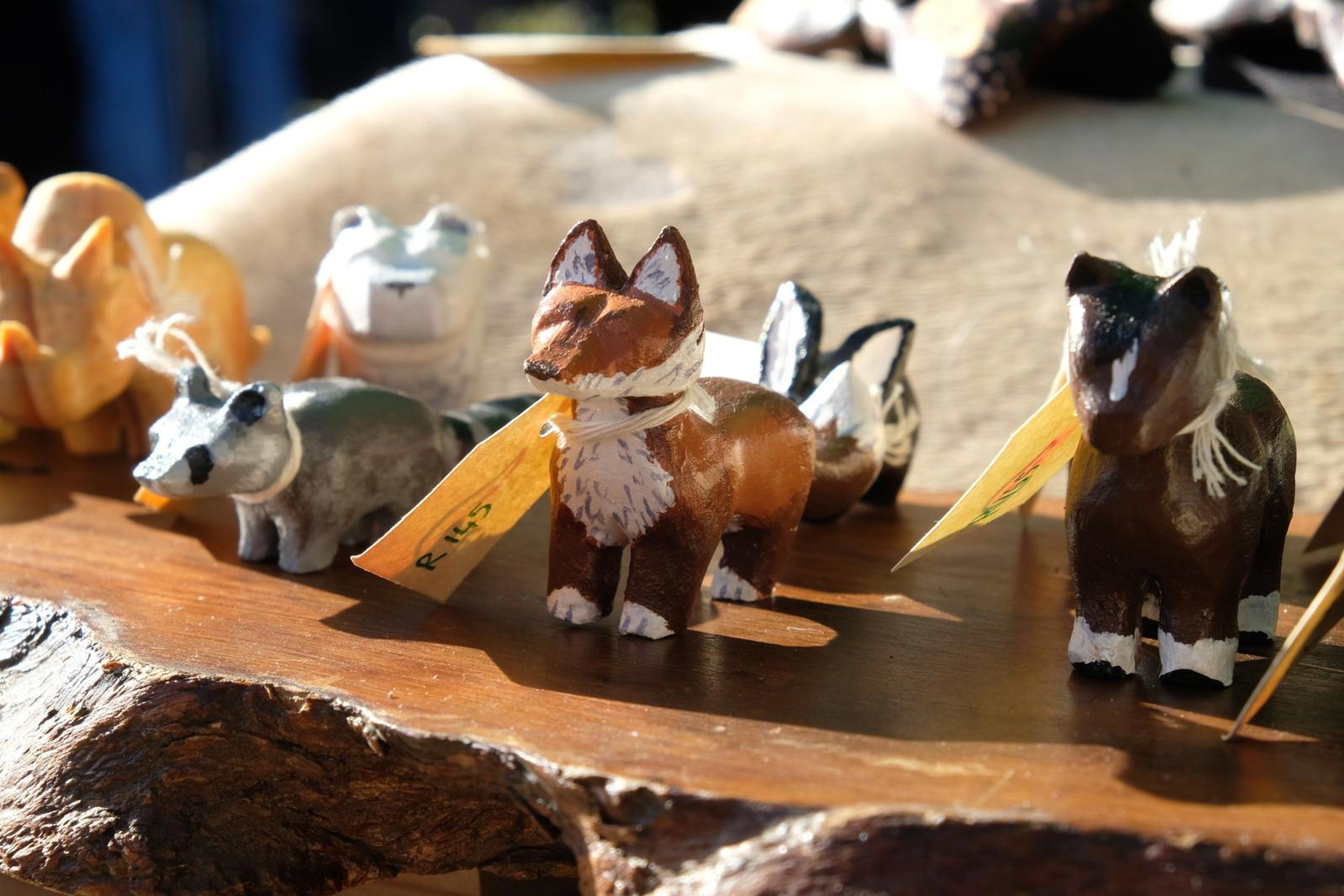 Hand-carved wooden fox, horse and wolf figures on a live-edge slab